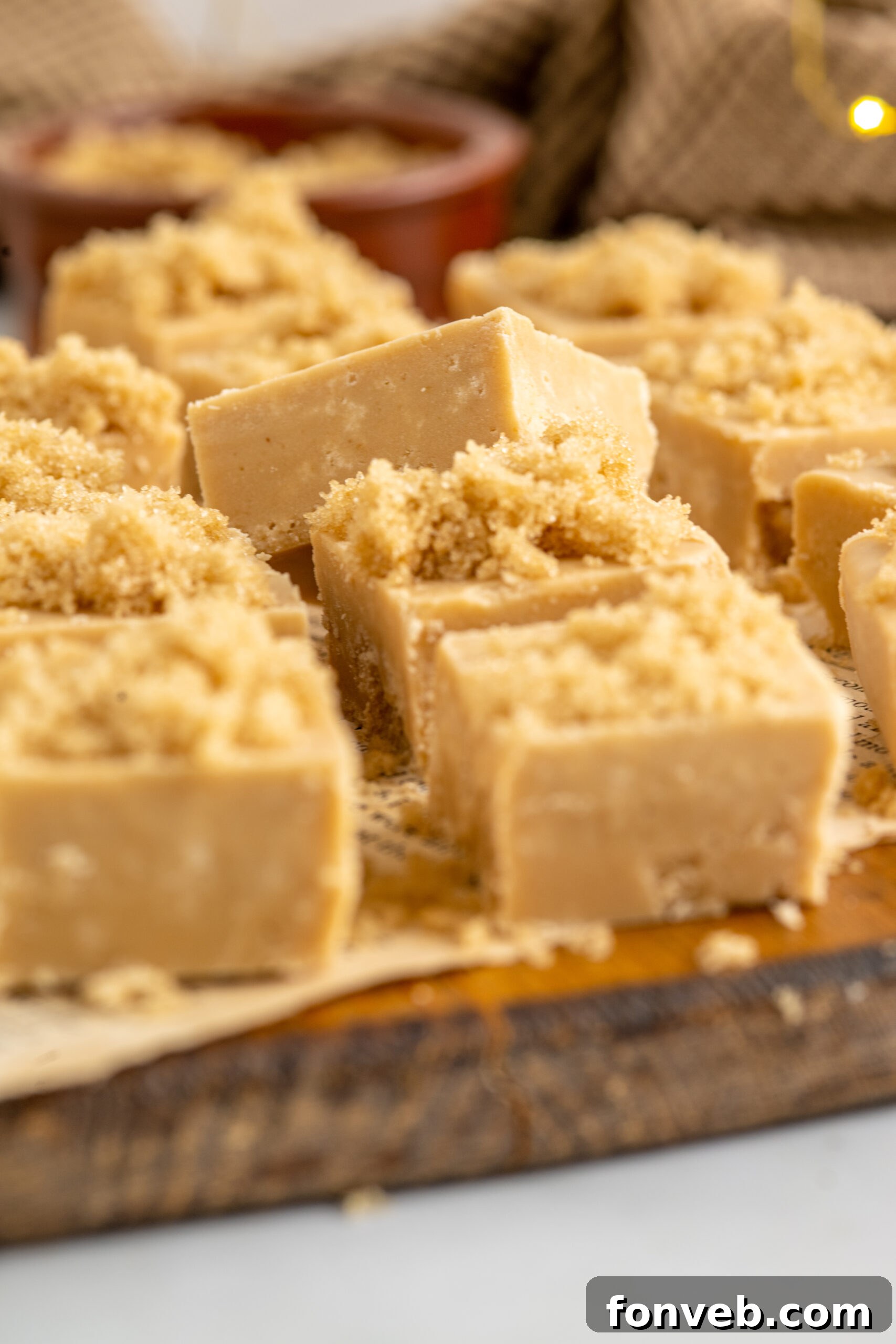Side view of freshly cut Penuche Fudge squares on a wooden board, ready to serve.