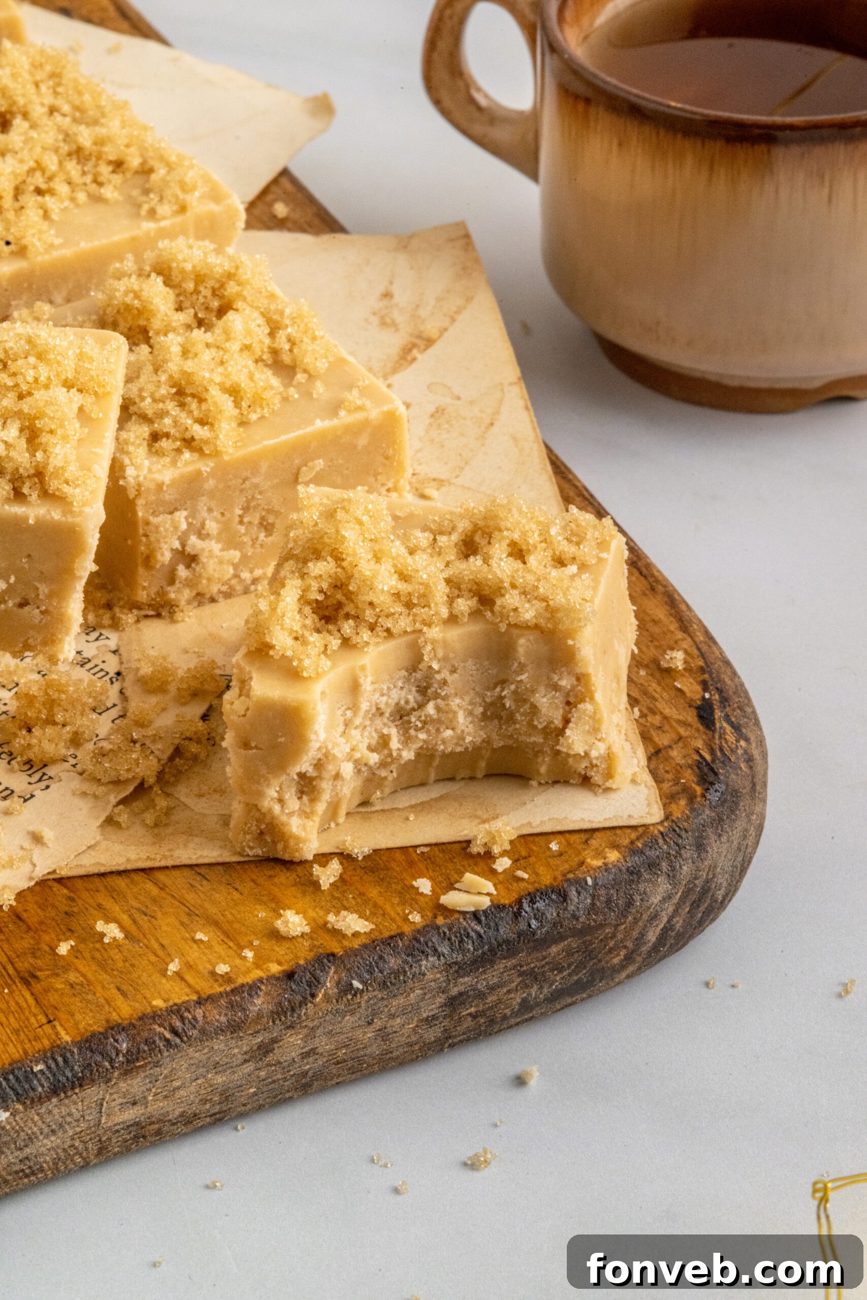 A piece of Penuche Fudge with a bite taken out, resting on a wooden board, highlighting its soft interior.