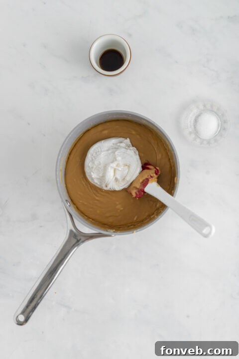 The fudge mixture simmering gently on the stove, with a candy thermometer showing temperature.