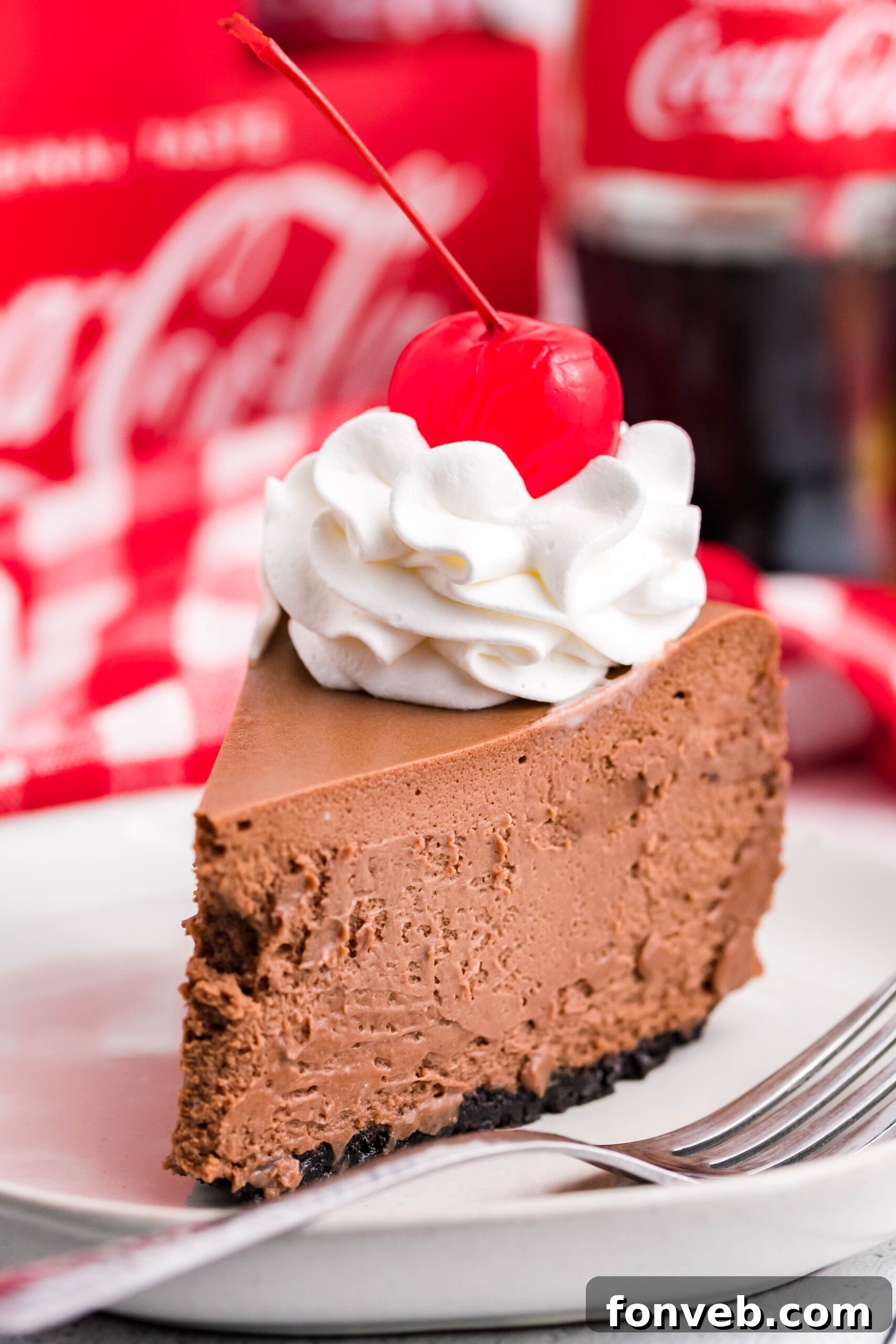 Side view of a slice of Coca Cola Cheesecake on a white dish, showcasing its inviting layers.