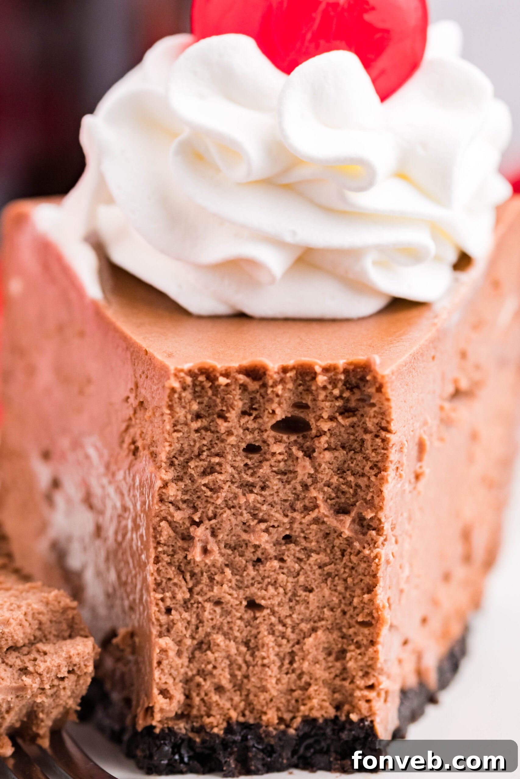 Front view of a slice of Coca Cola Cheesecake with a piece removed by a fork, ready to be enjoyed.