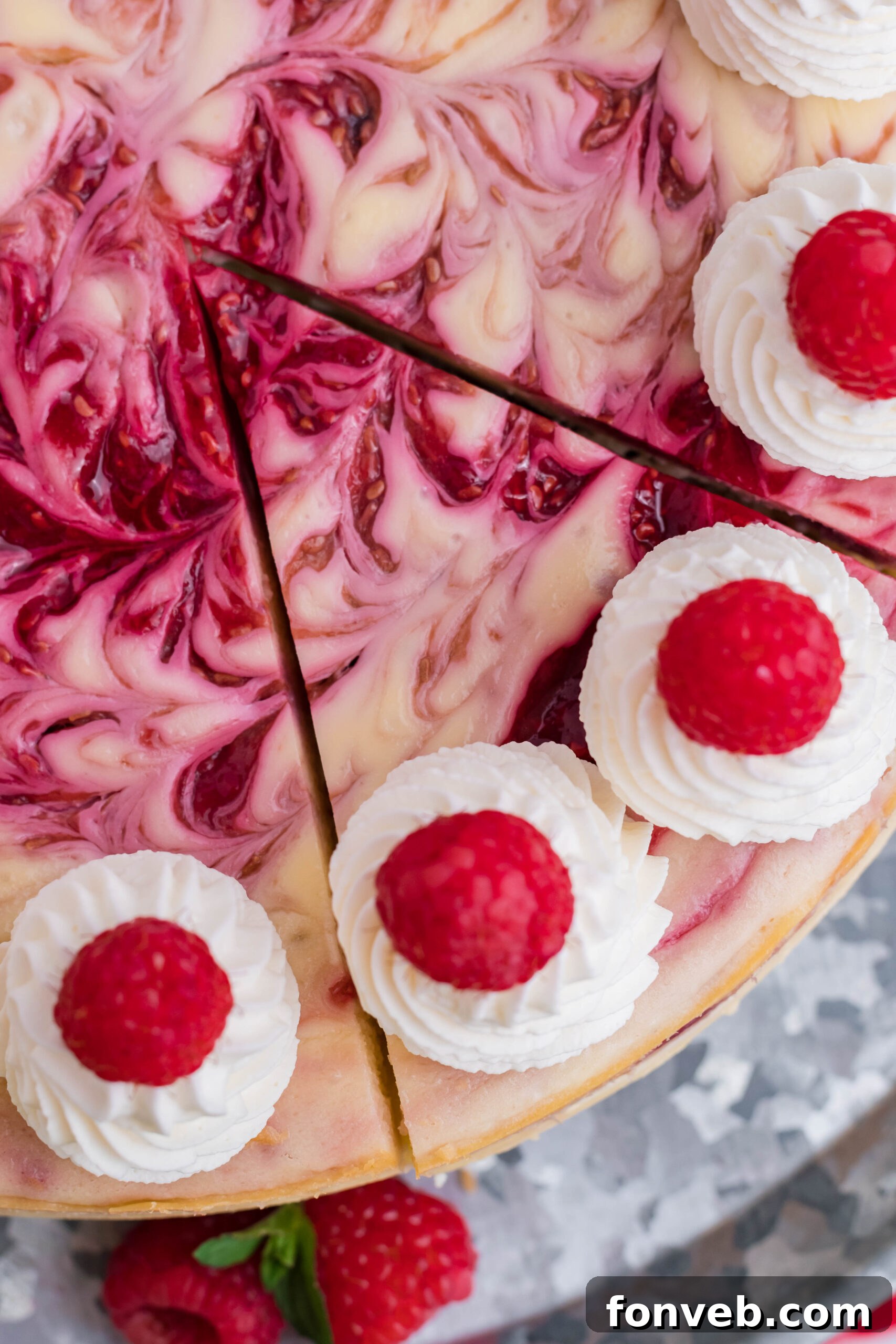 Close-up overhead view of a Raspberry Swirl Cheesecake with a perfect slice removed, revealing the creamy interior and distinct swirl patterns.