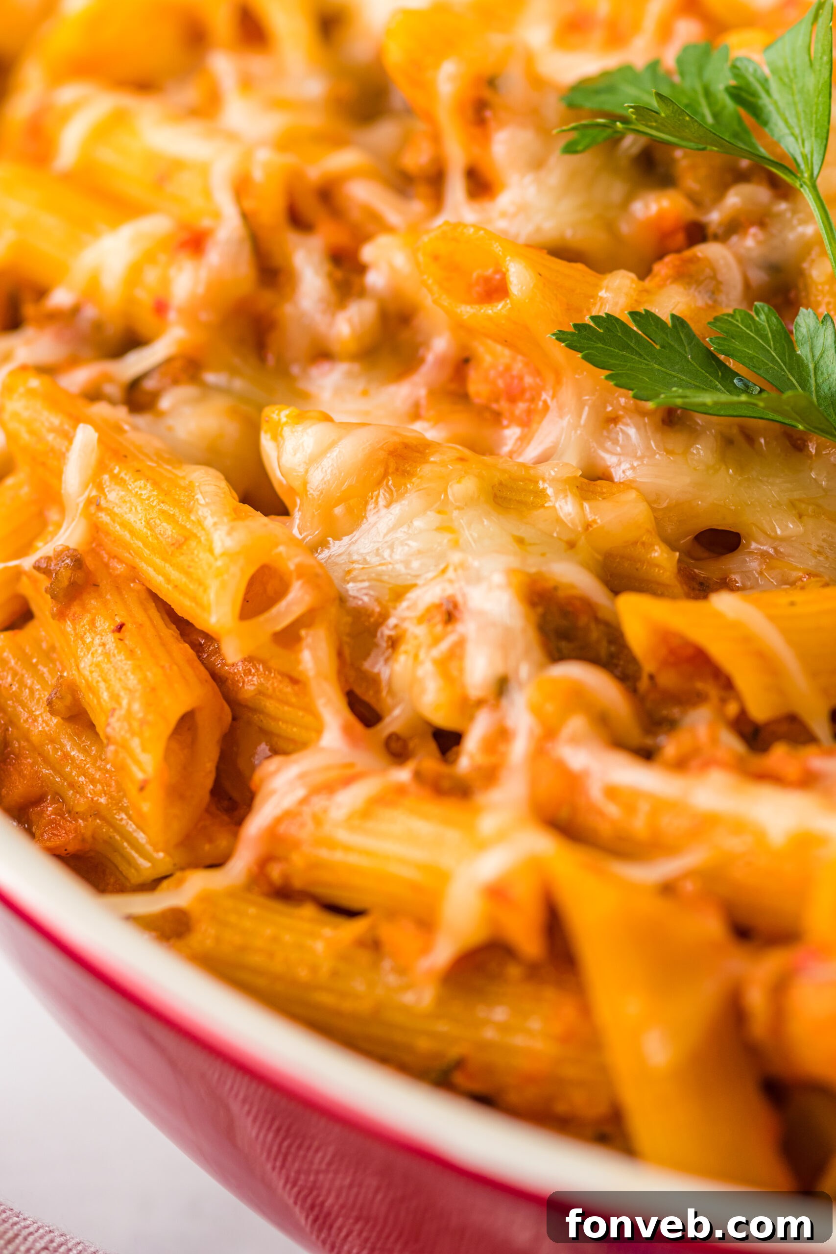 Pasta Fagioli Bake 3 Close up view of Pasta Fagioli al Forno in a baking dish, highlighting the melted cheese and a glimpse of the pasta and bean mixture underneath.