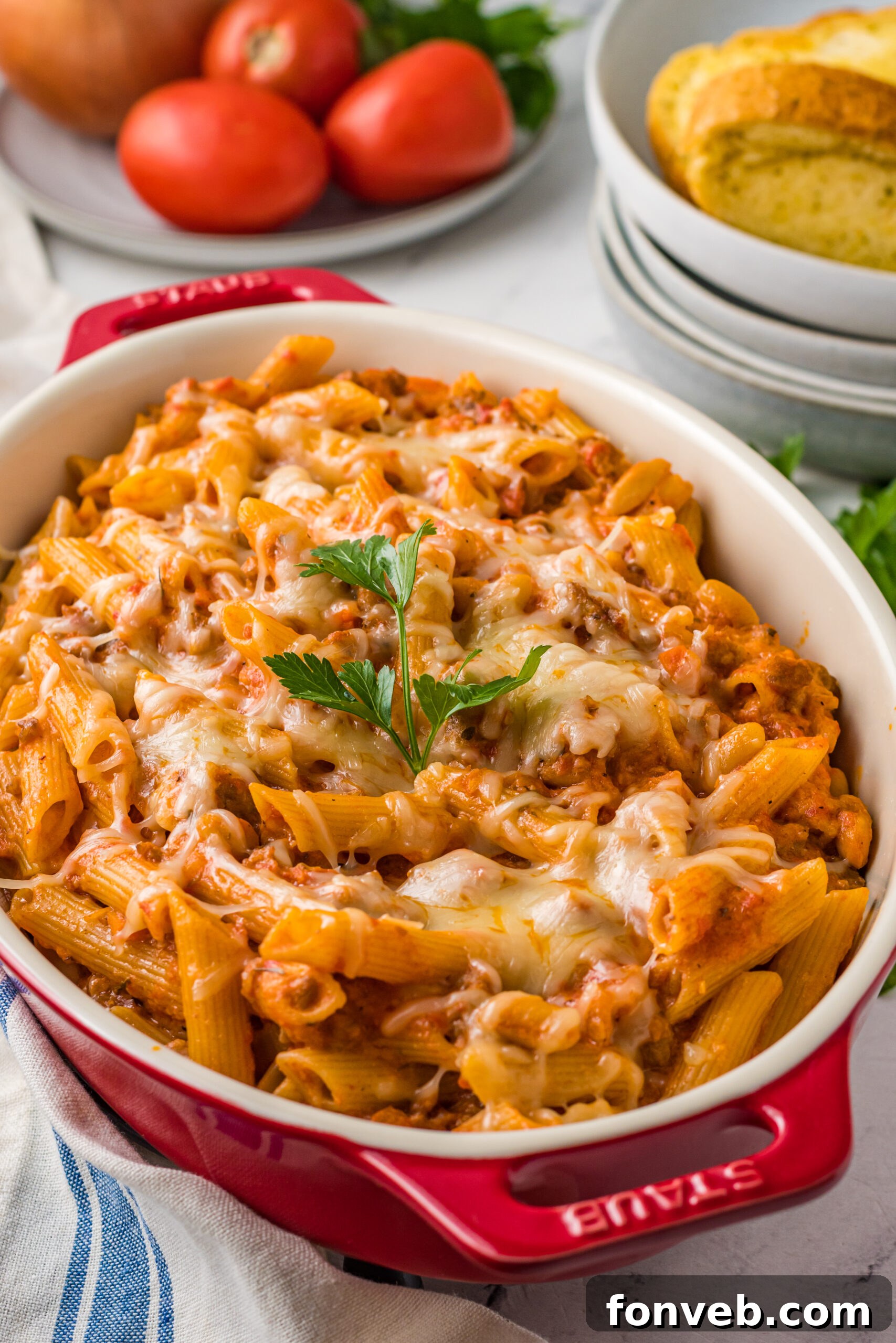Pasta Fagioli Bake 4 Close up view of Pasta Fagioli al Forno in a baking dish with a wooden spoon scooping a serving, revealing layers of pasta, sausage, and cheese.