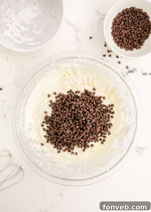 Mini chocolate chips being folded into the creamy dip mixture.