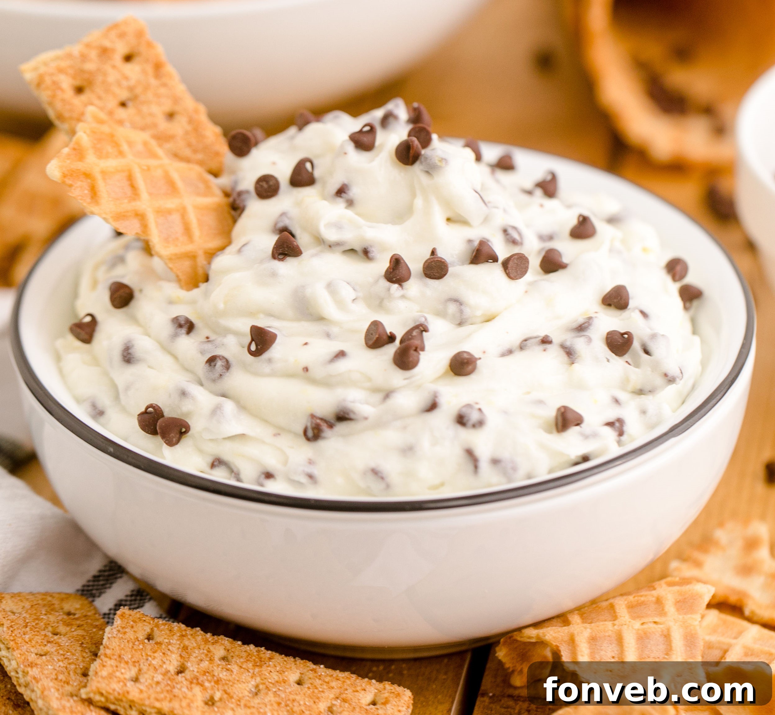 An inviting close-up shot of the finished Cannoli Dip in a white dish, garnished with a waffle cone, highlighting its rich texture.