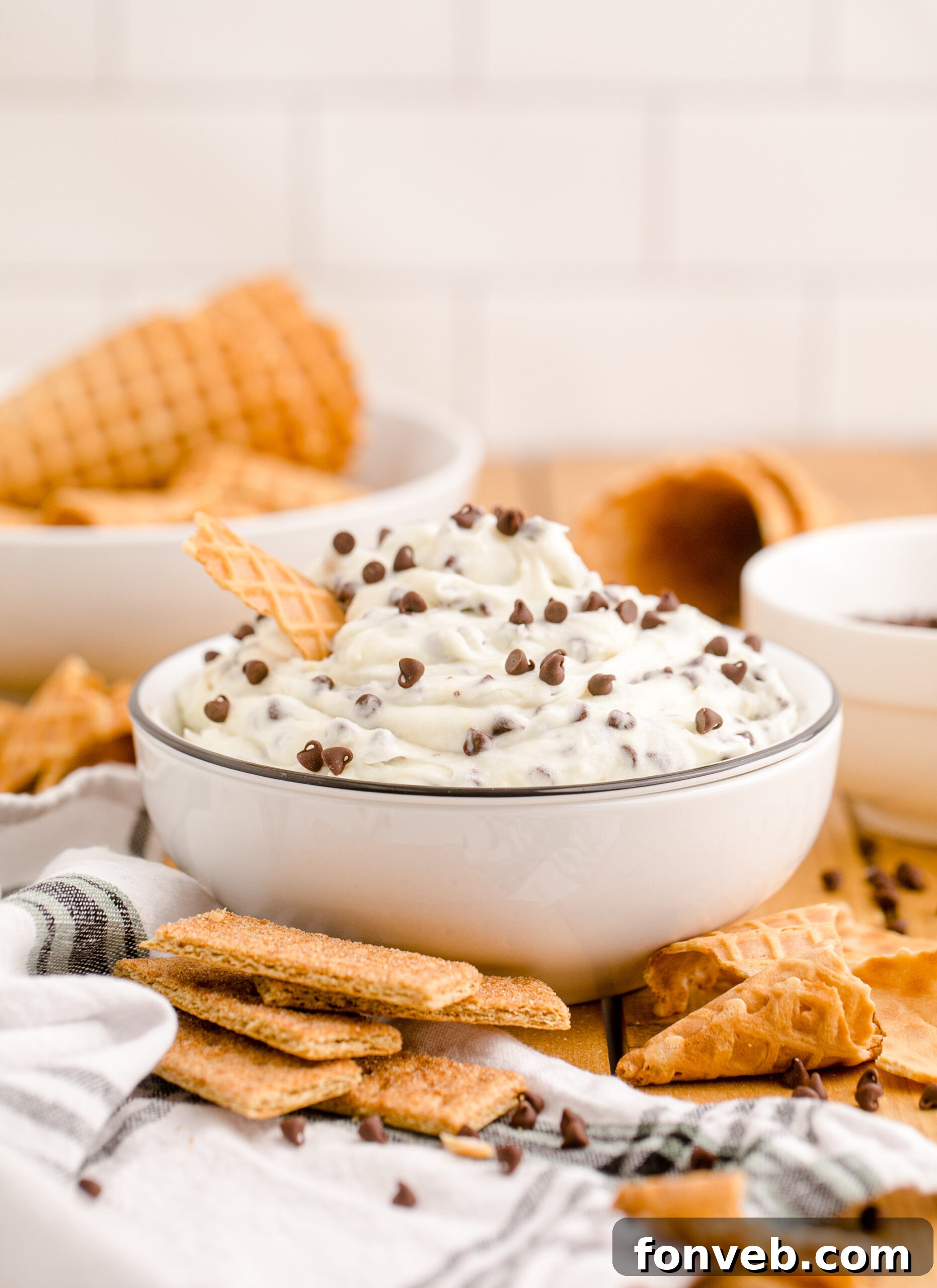 Side view of the finished Cannoli Dip, beautifully presented in a black and white bowl with a waffle cone, gleaming under soft light.