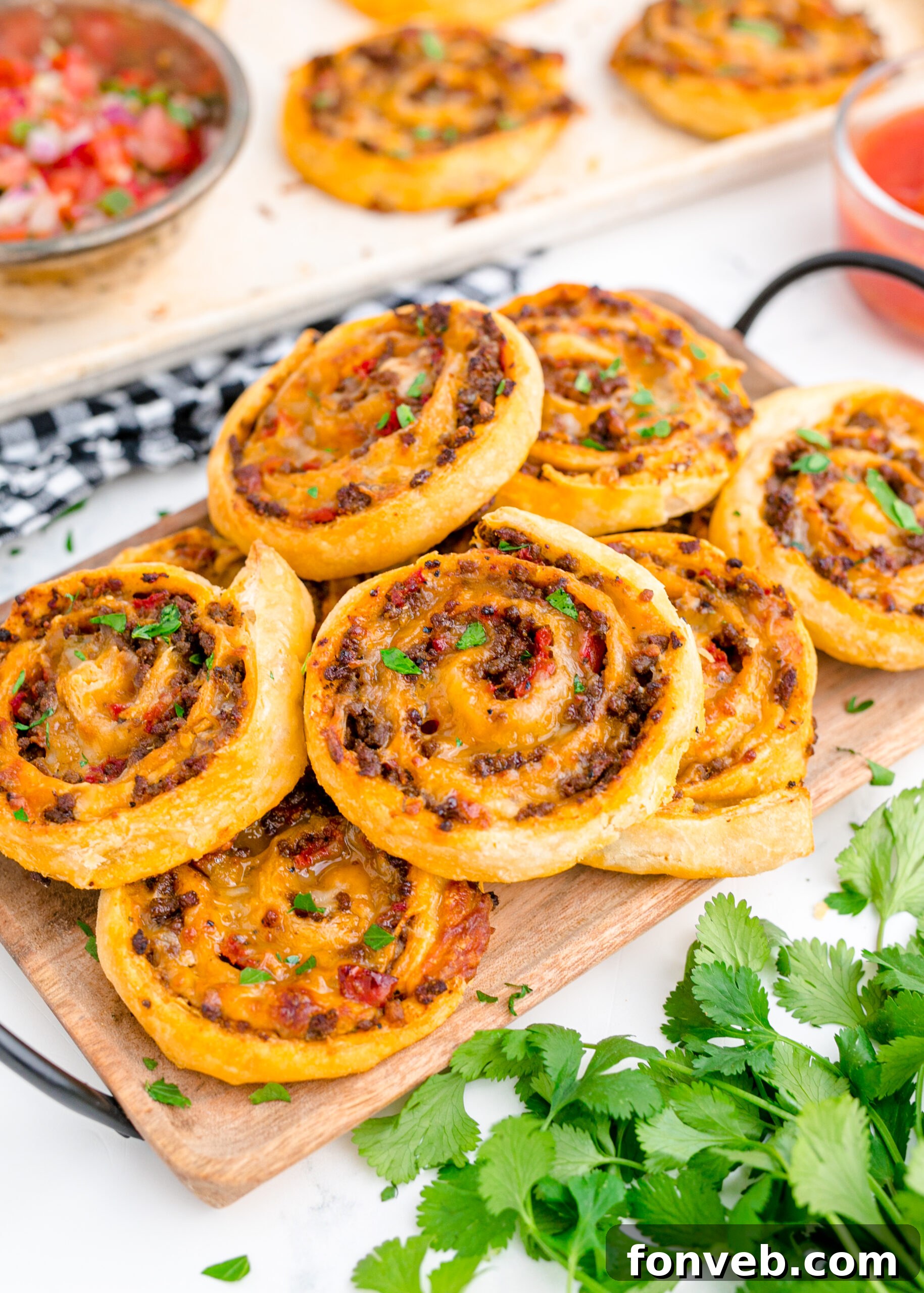 Side view of Taco Pinwheels stacked on a wooden cutting board.