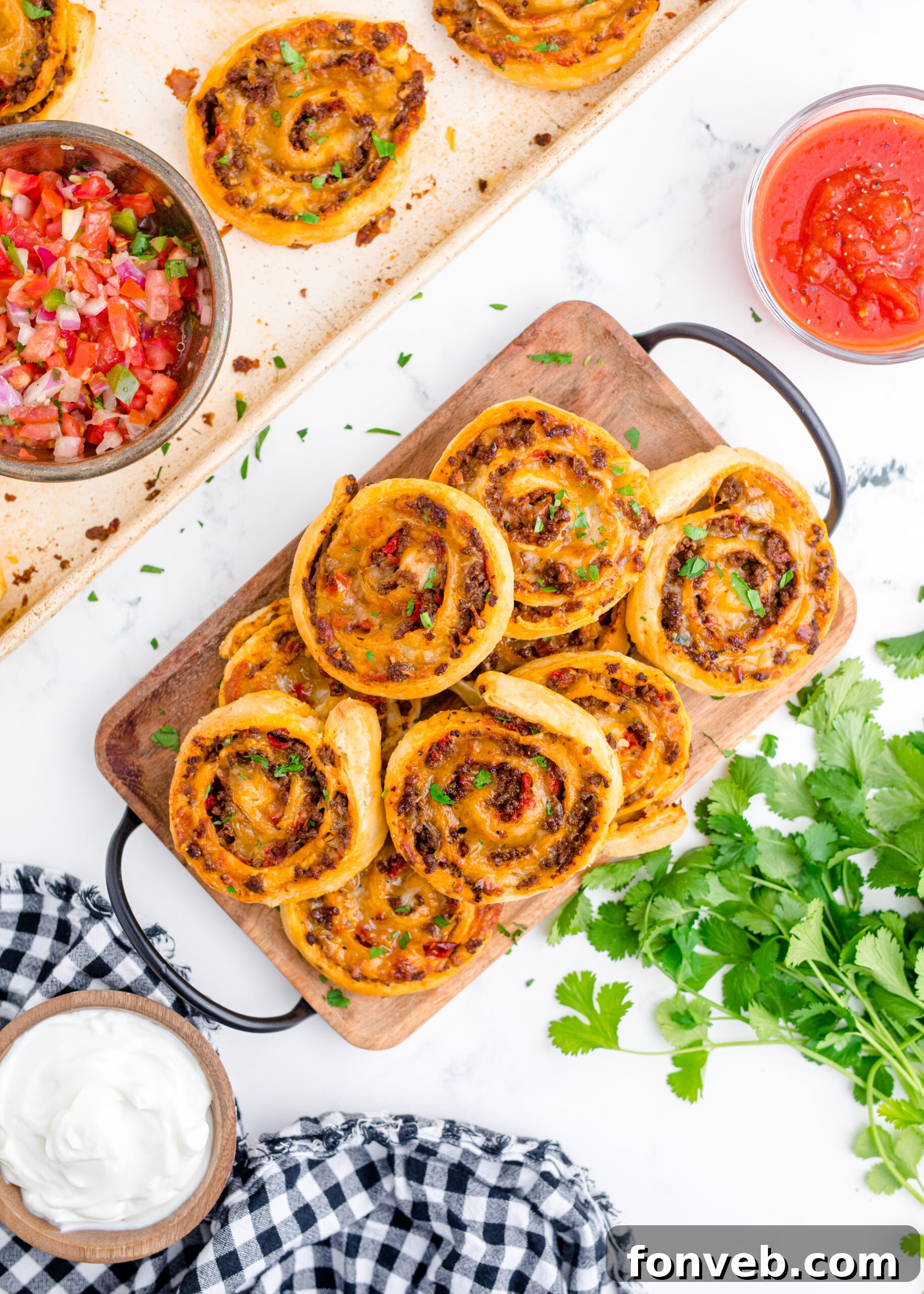 Overhead view of Taco Pinwheels stacked on a wooden cutting board.