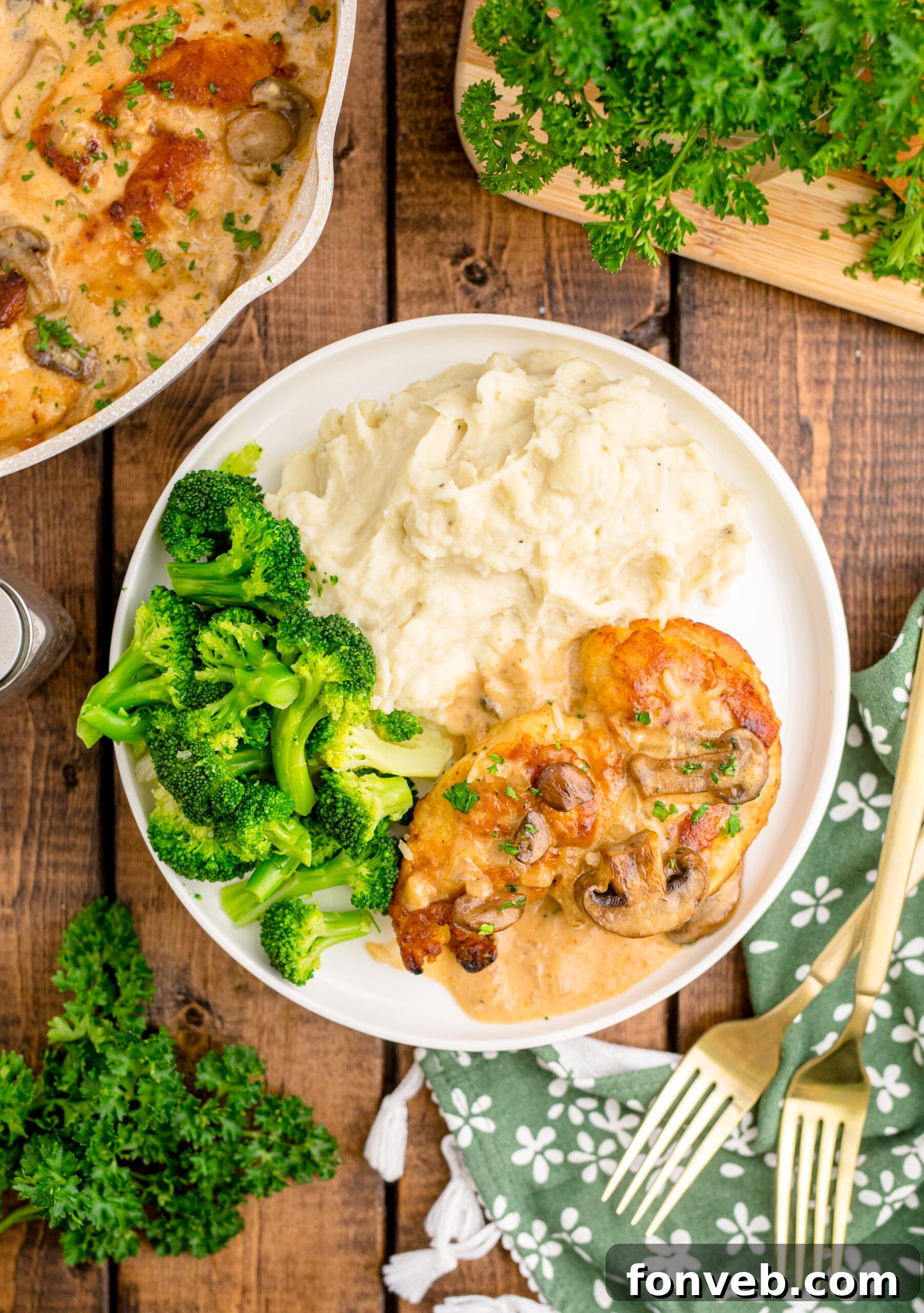 Overhead view of Chicken Marsala on a white dish served with mashed potatoes and broccoli.