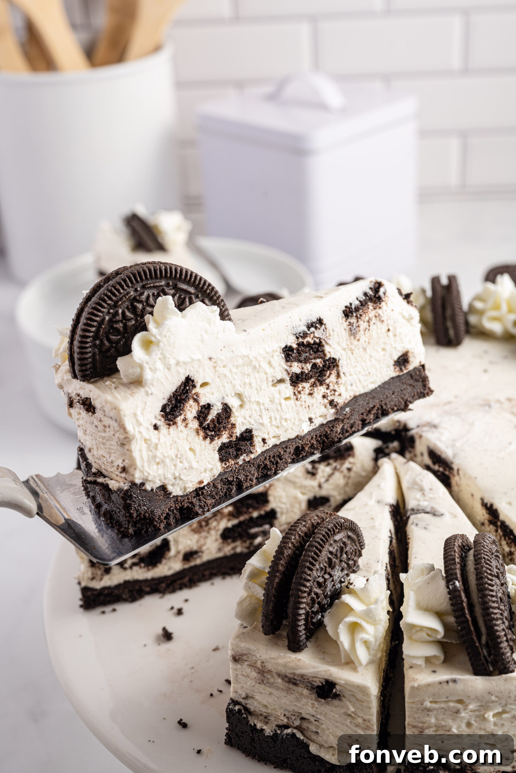 Side view of a slice of No Bake Oreo Cheesecake on a silver spatula, showcasing its creamy layers and crumbly crust.