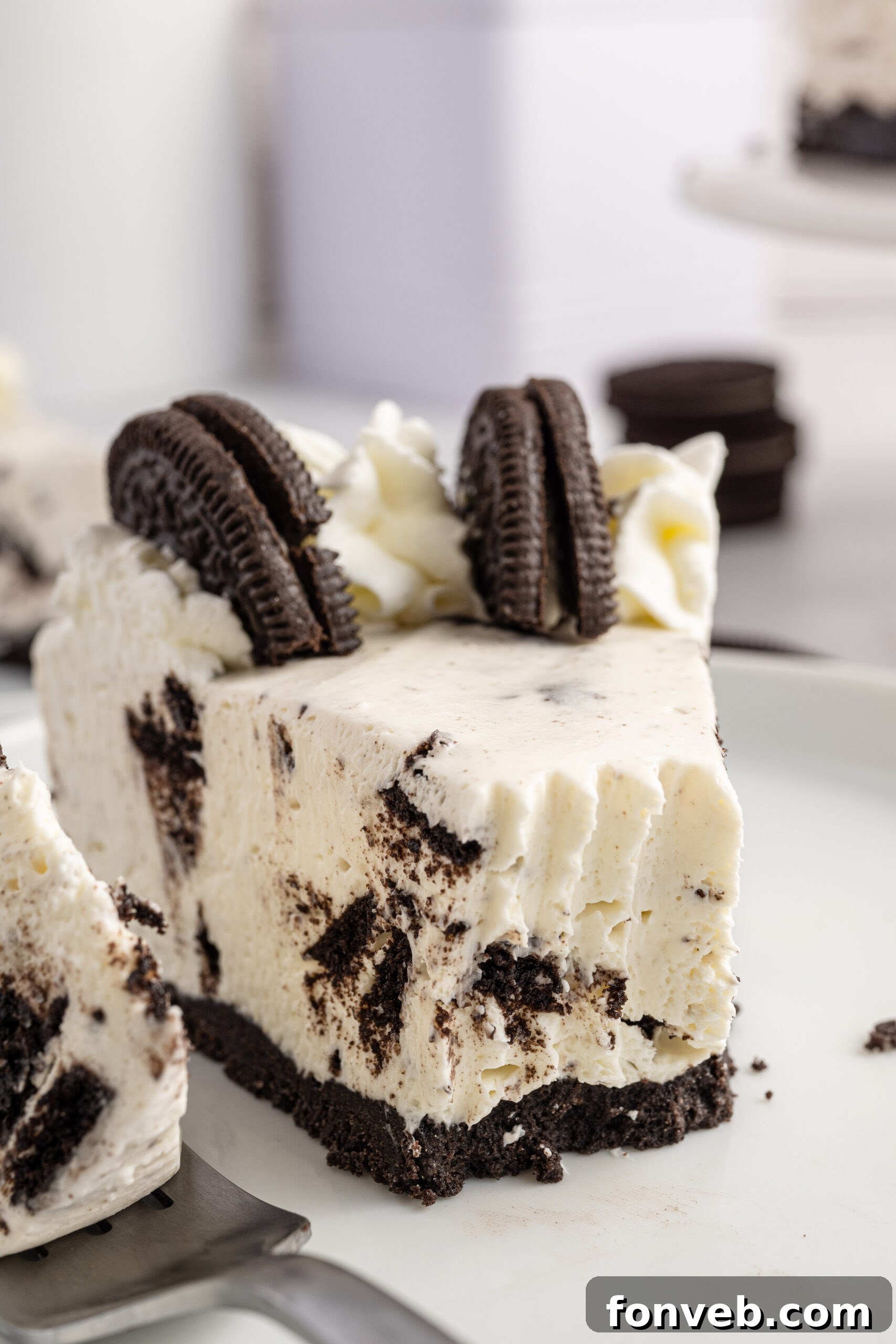 Up close view of No Bake Oreo Cheesecake with a piece removed with a silver fork, highlighting the creamy texture.