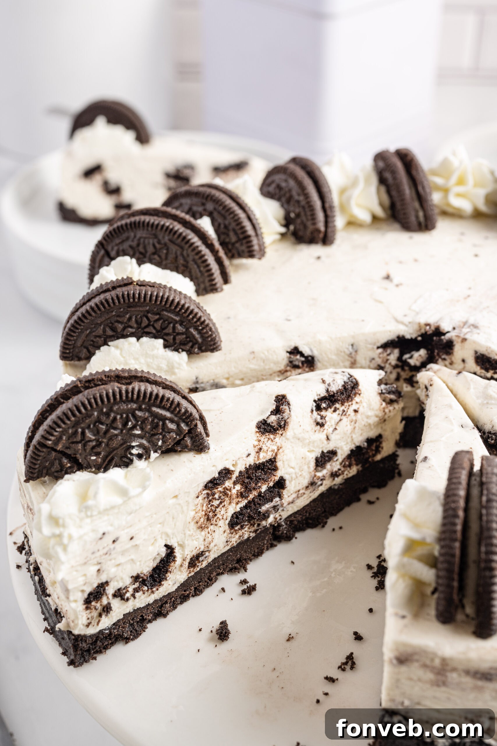Close up view of No Bake Oreo Cheesecake with 3 slices cut and one removed, showing the creamy filling and visible Oreo pieces.