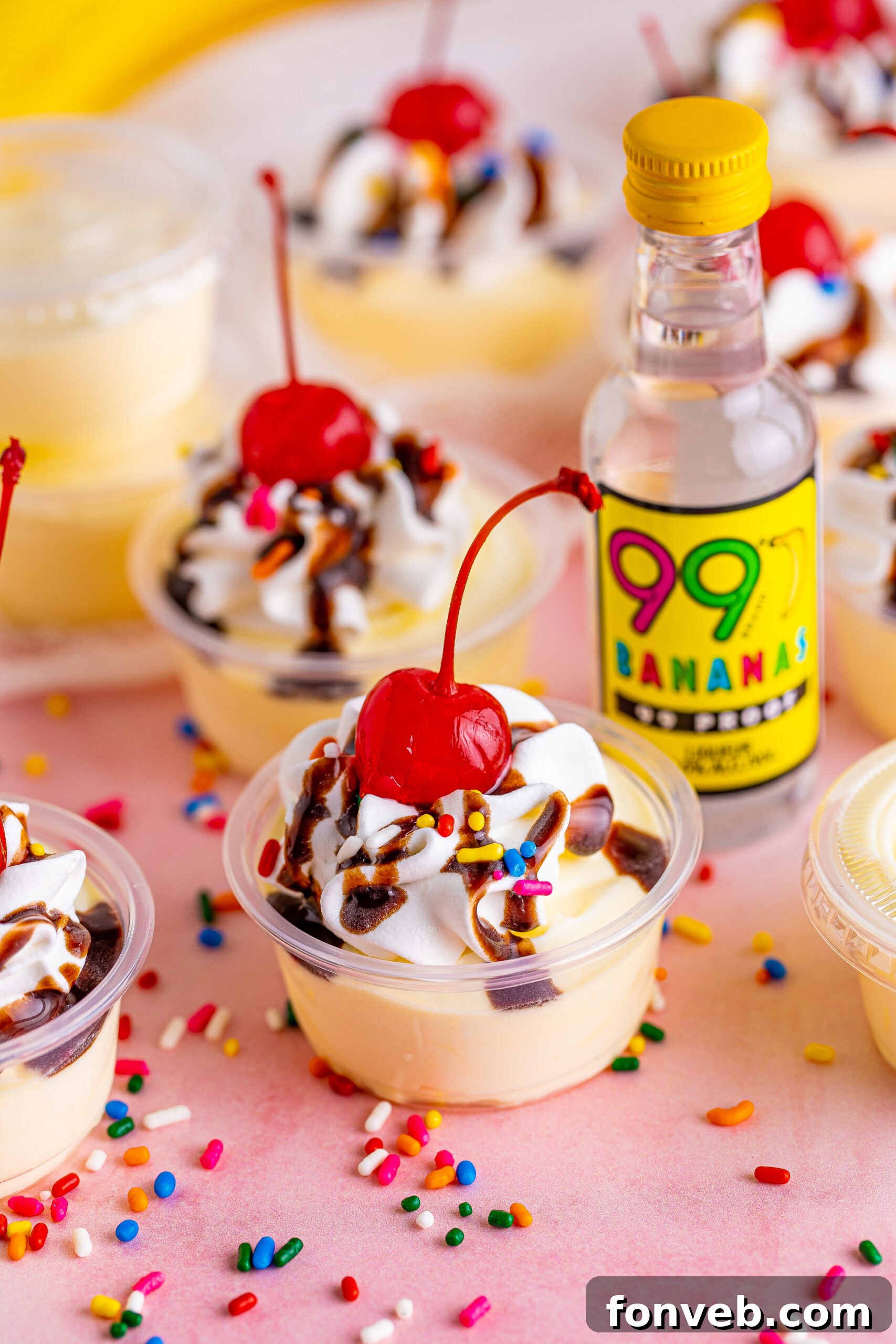 Mini Banana Split Delights 2 Side view of Banana Split Shots surrounded by rainbow sprinkles, highlighting their creamy texture and vibrant toppings.