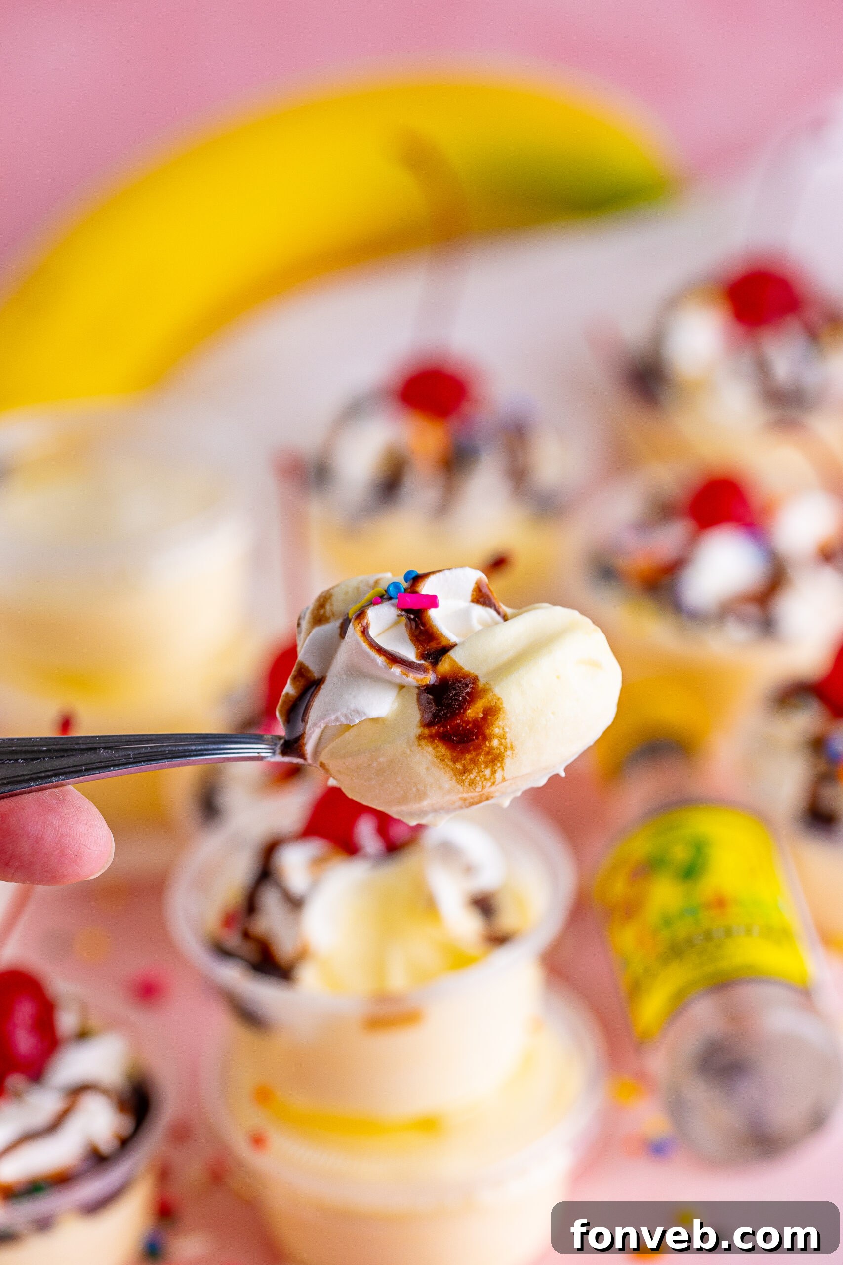 Mini Banana Split Delights 17 Silver spoon holding a perfect spoonful of Banana Split Shots, showcasing the creamy layers and colorful toppings.