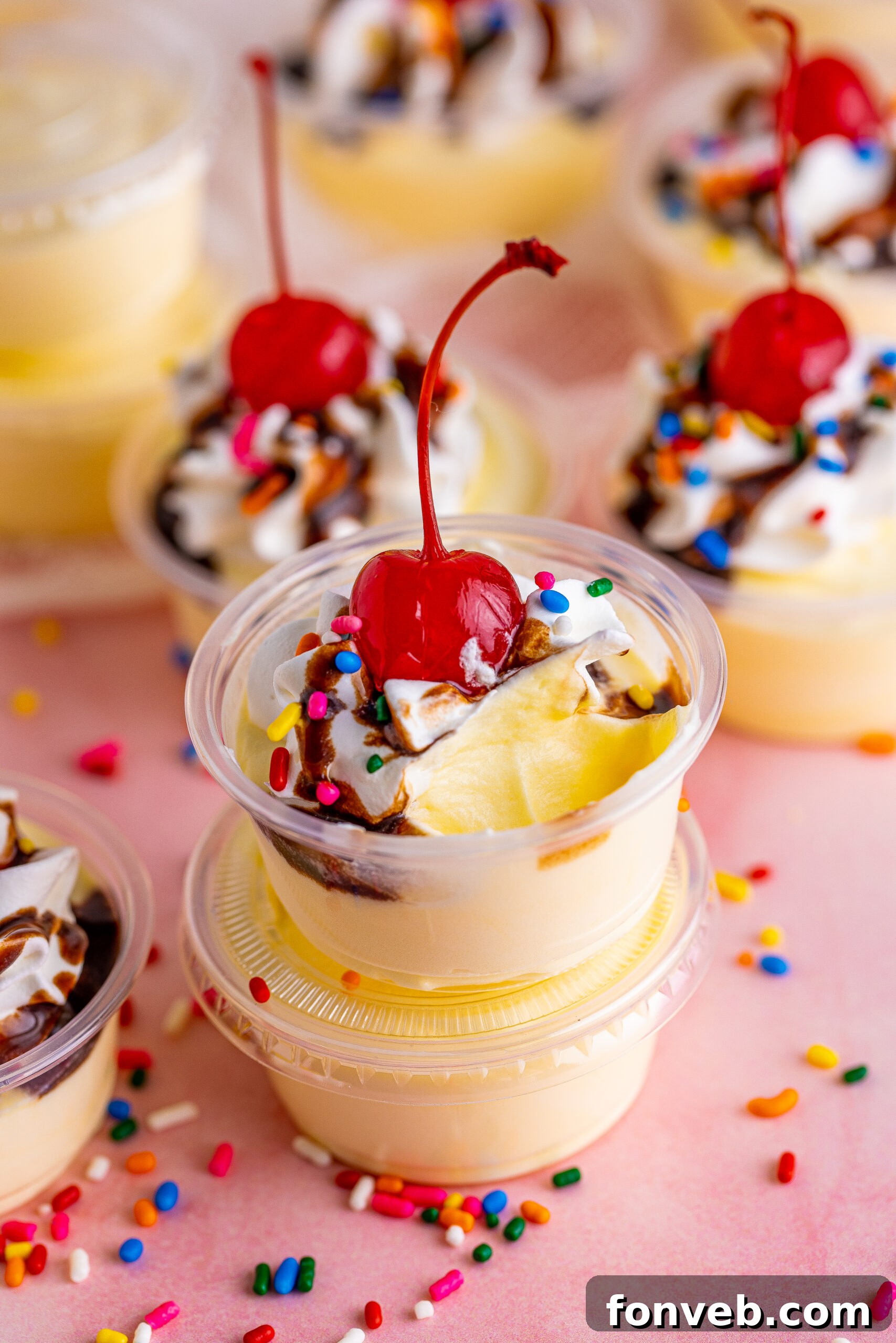 Mini Banana Split Delights 5 Side view of Banana Split Shots stacked, with a spoon removing a portion from the top shot, emphasizing its creamy texture.