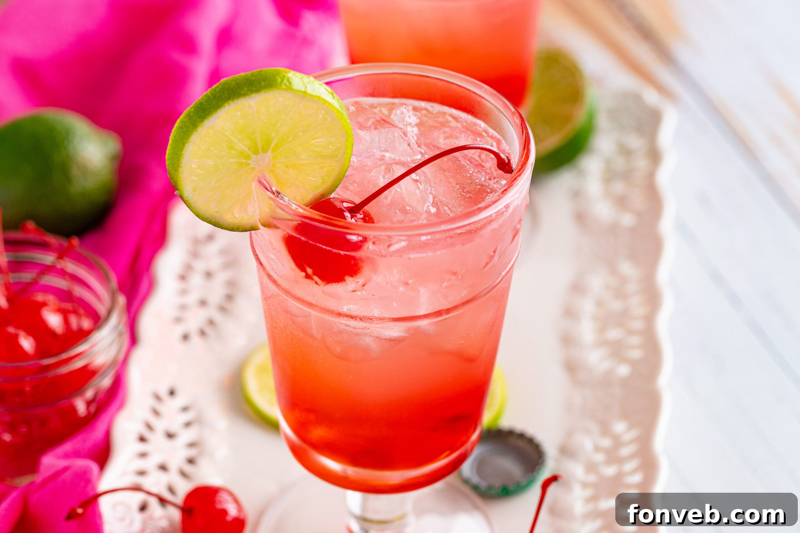 45-degree view of a Dirty Shirley Temple garnished with a lime slice, showcasing its vibrant color.
