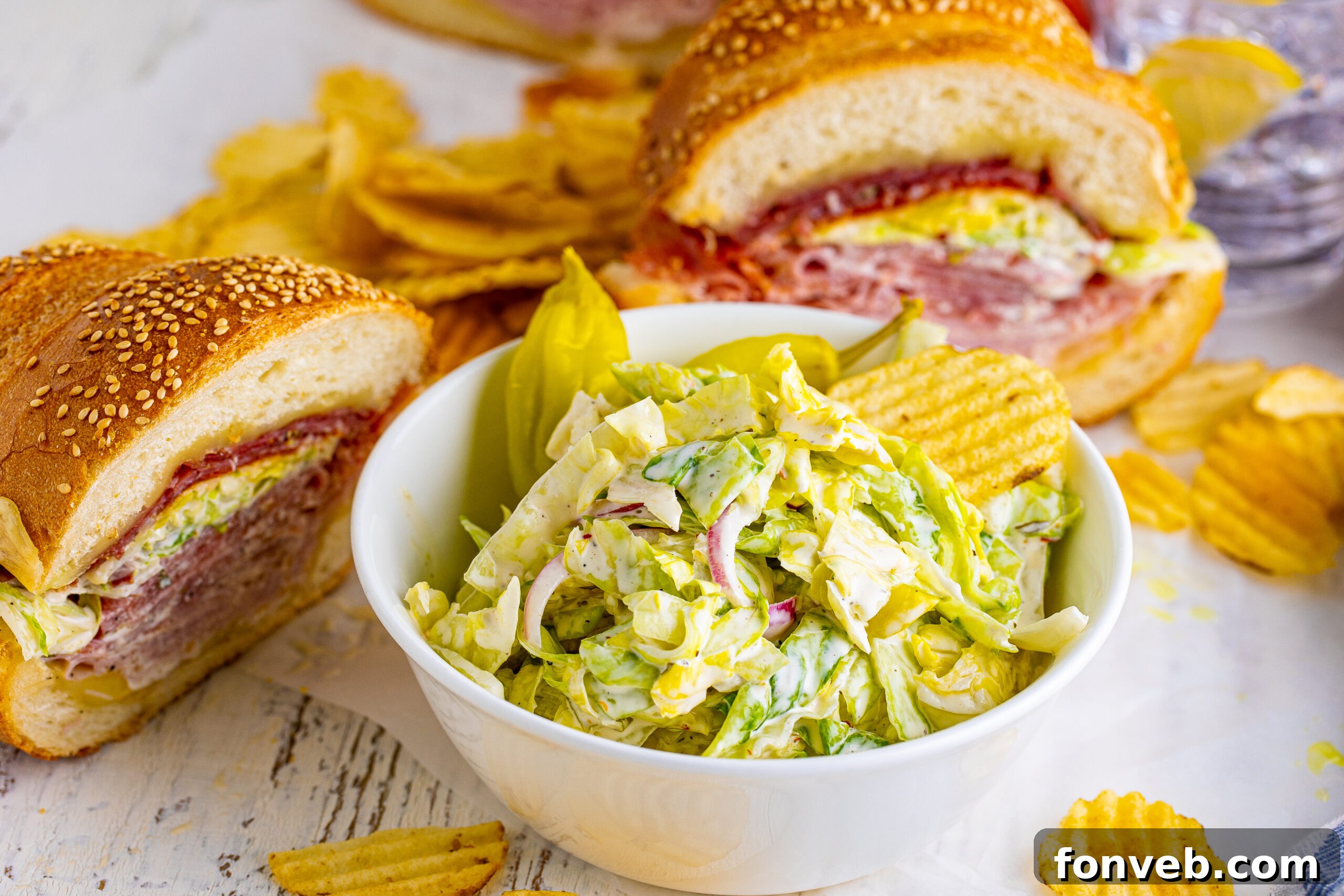 Grinder salad in a white bowl with the sliced grinder sub in the background 