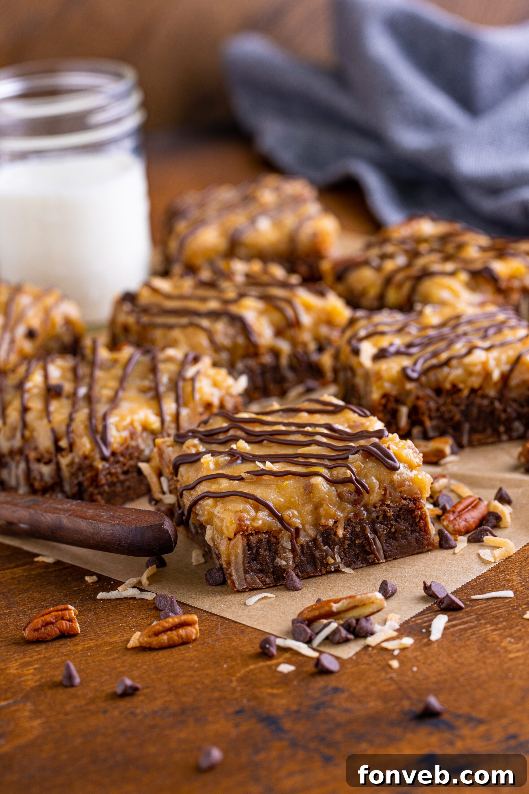 Side view of a tray of freshly baked German Chocolate Brownies on a piece of parchment paper, highlighting their thick, layered texture.