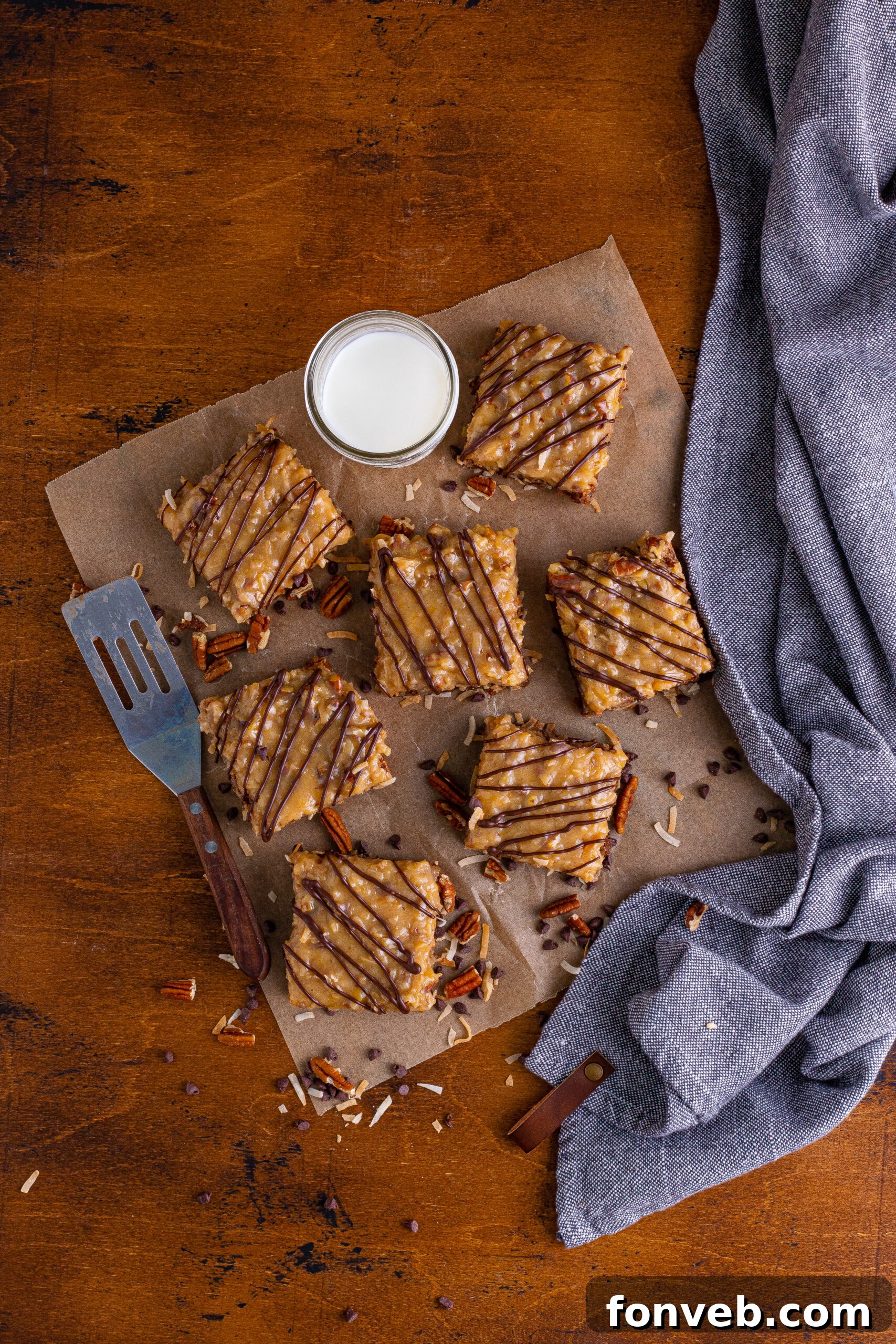 Overhead view of a batch of German Chocolate Brownies on a piece of parchment paper, garnished and ready to be sliced.