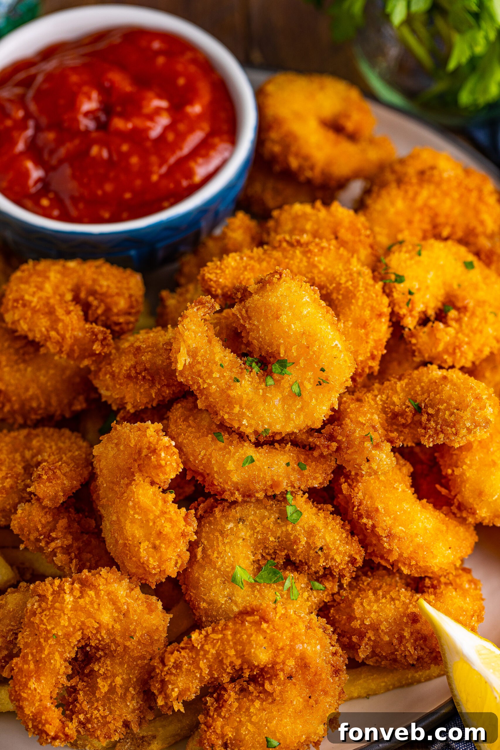 overhead view of Panko Fried Shrimp on a dish served with cocktail sauce and lemon wedges.
