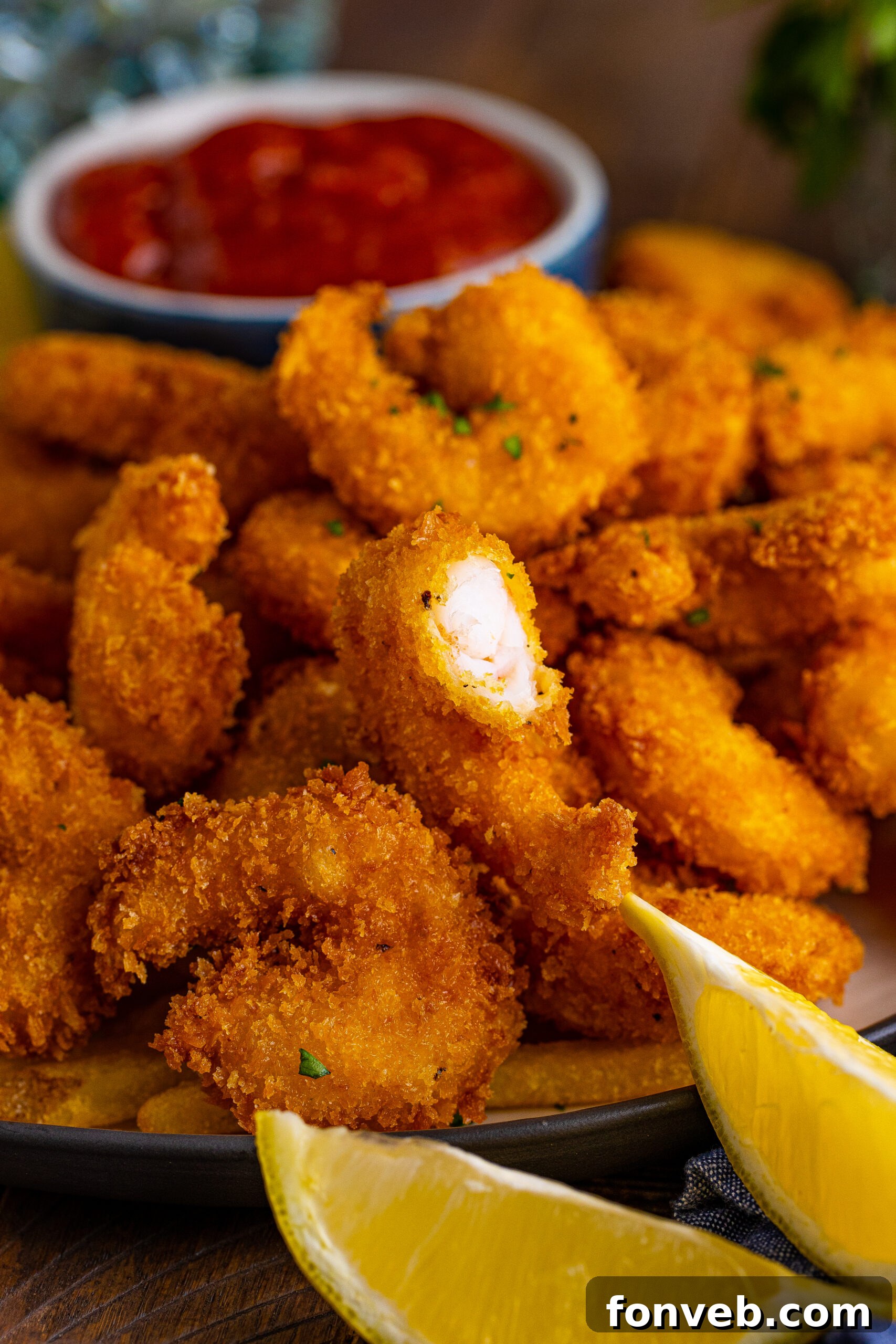Front view of Panko Fried Shrimp on a dish served with french fries, cocktail sauce and lemon wedges.