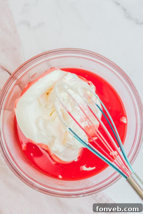 Luscious Raspberry Whip 11 Ingredients for Raspberry Jello Fluff being mixed in a bowl.