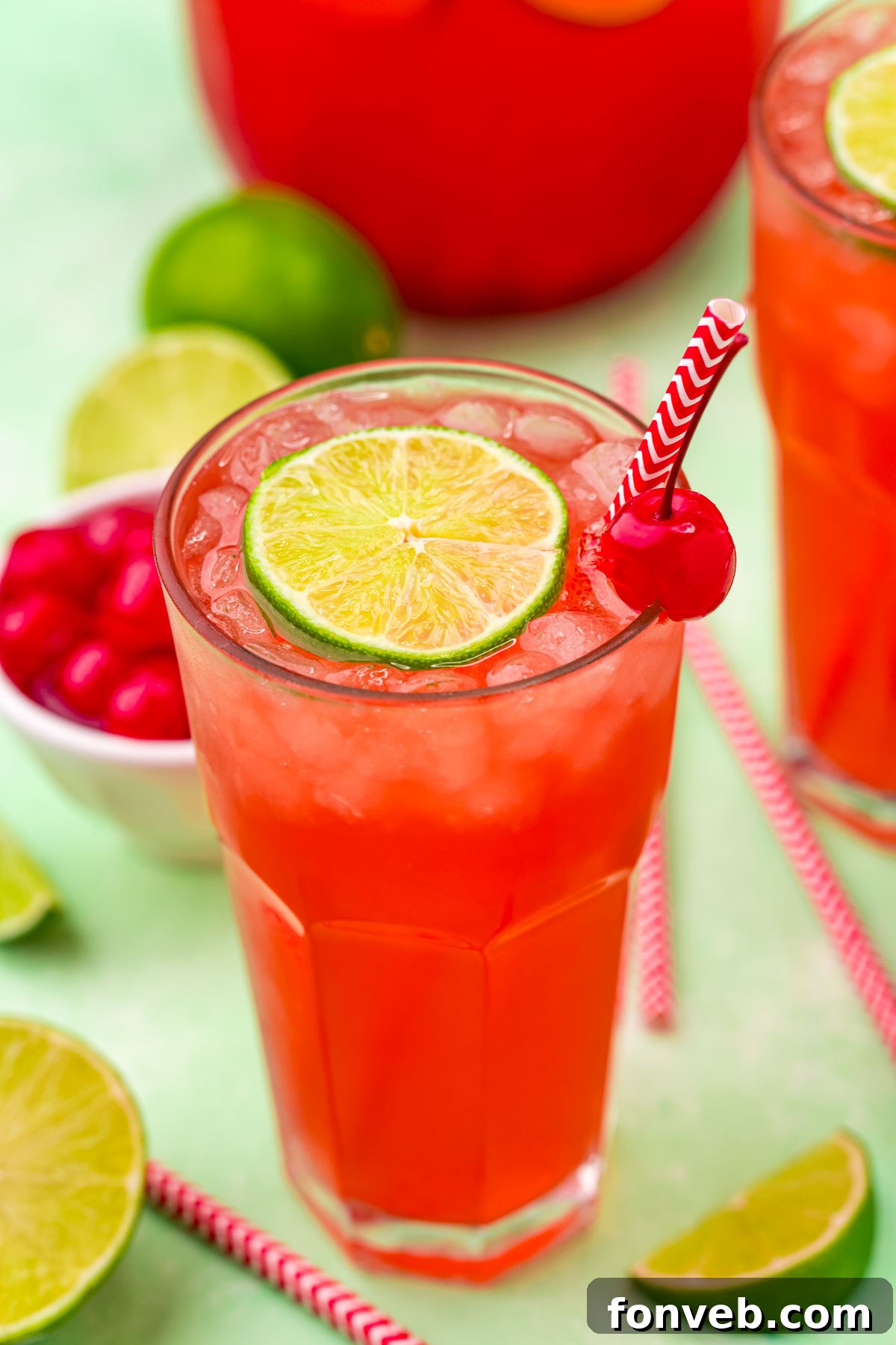 Crimson Zest Quencher 2 A glass of vibrant red Cherry Limeade, garnished with a fresh lime slice and a bright red maraschino cherry, ready to be enjoyed on a hot day.