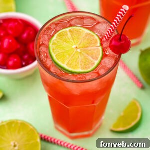 A glass of Cherry Limeade garnished with a lime and cherry.
