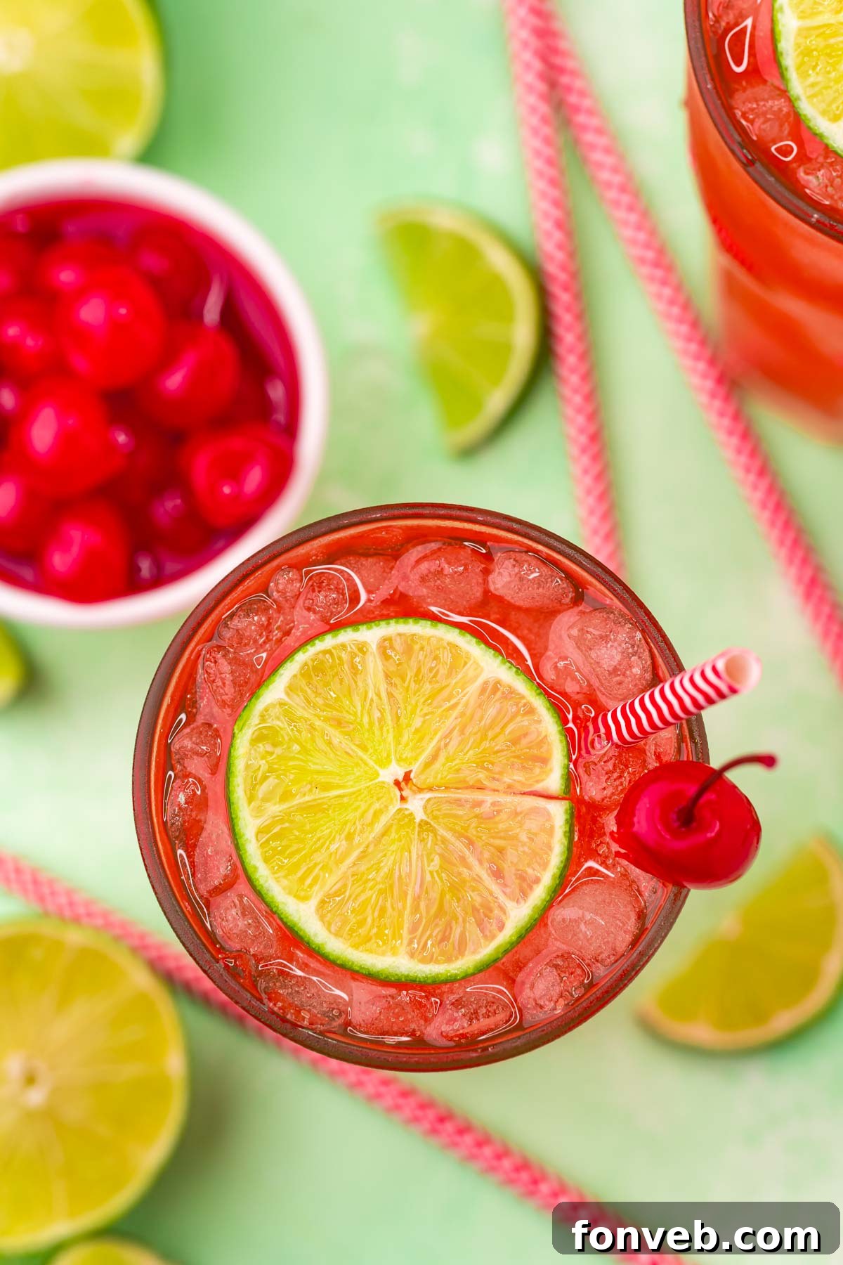 Crimson Zest Quencher 3 An overhead shot of a refreshing Cherry Limeade, adorned with a bright green lime wedge and a glistening maraschino cherry, sitting on a light surface.