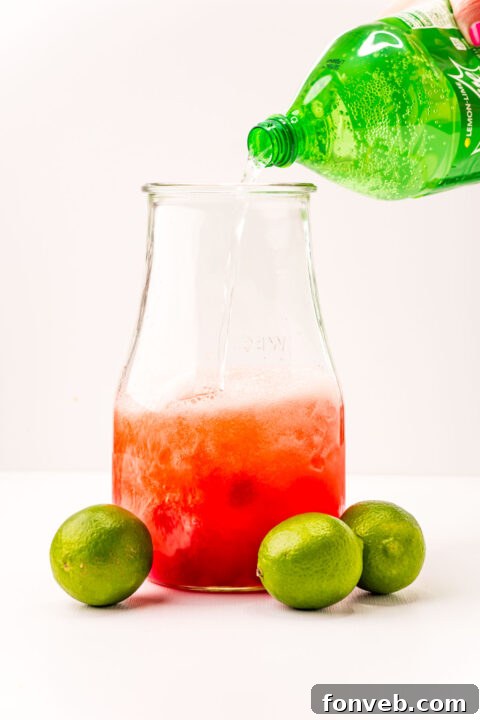 Crimson Zest Quencher 9 A hand stirring the ingredients in a large pitcher to thoroughly combine them, creating the Cherry Limeade mixture.