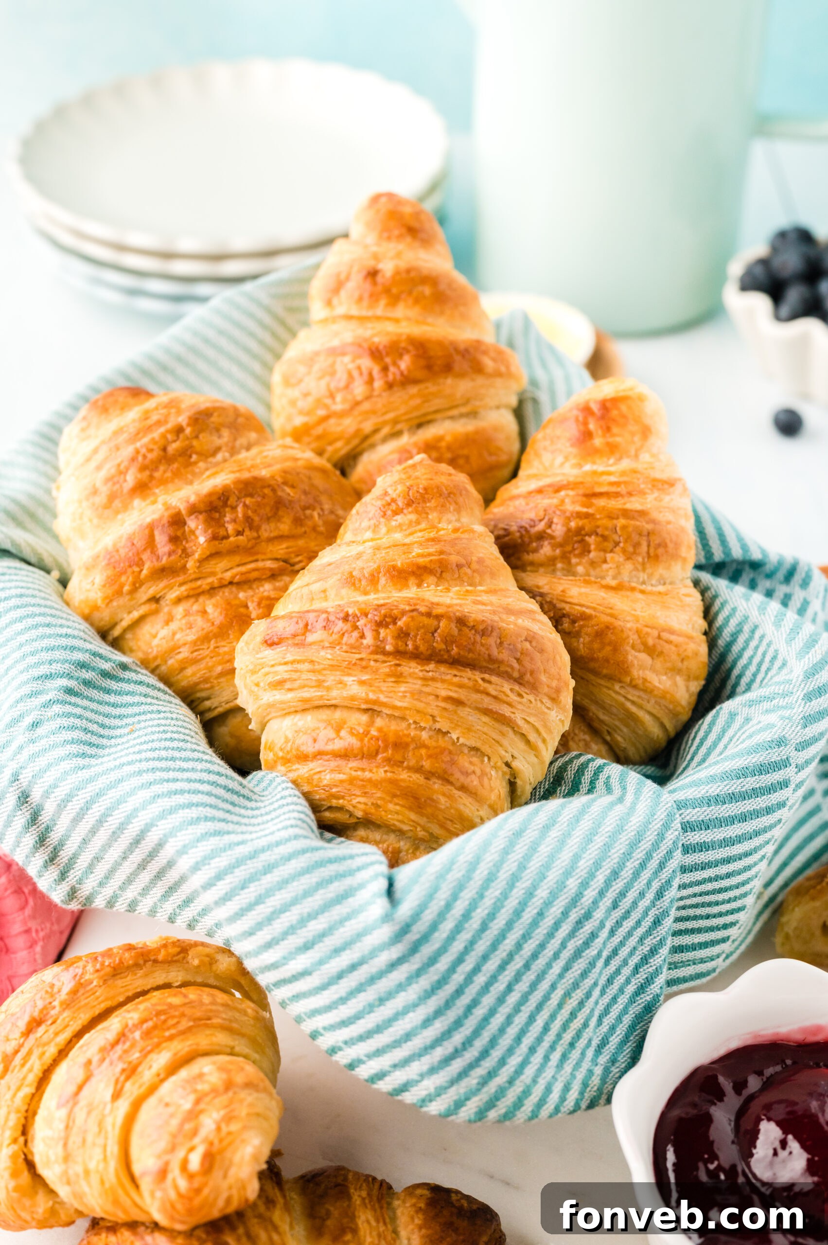 A basket full of golden, flaky homemade croissants, perfectly proofed and baked, ready to be enjoyed.