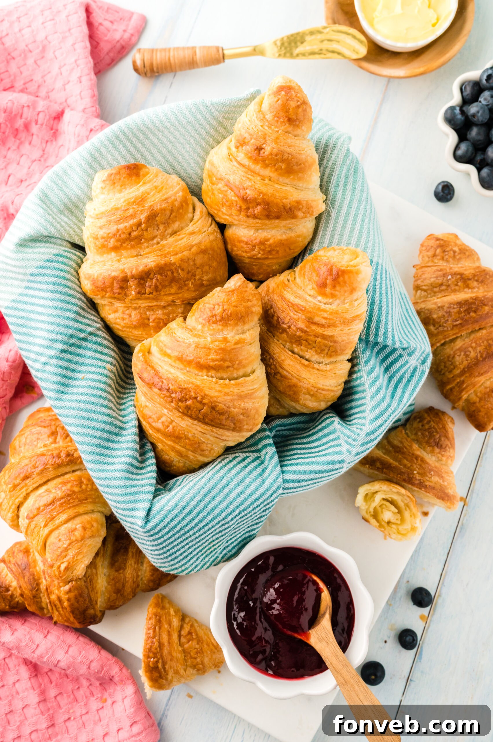 An inviting overhead view of freshly baked homemade croissants, nestled in a linen-lined basket, radiating warmth and deliciousness.