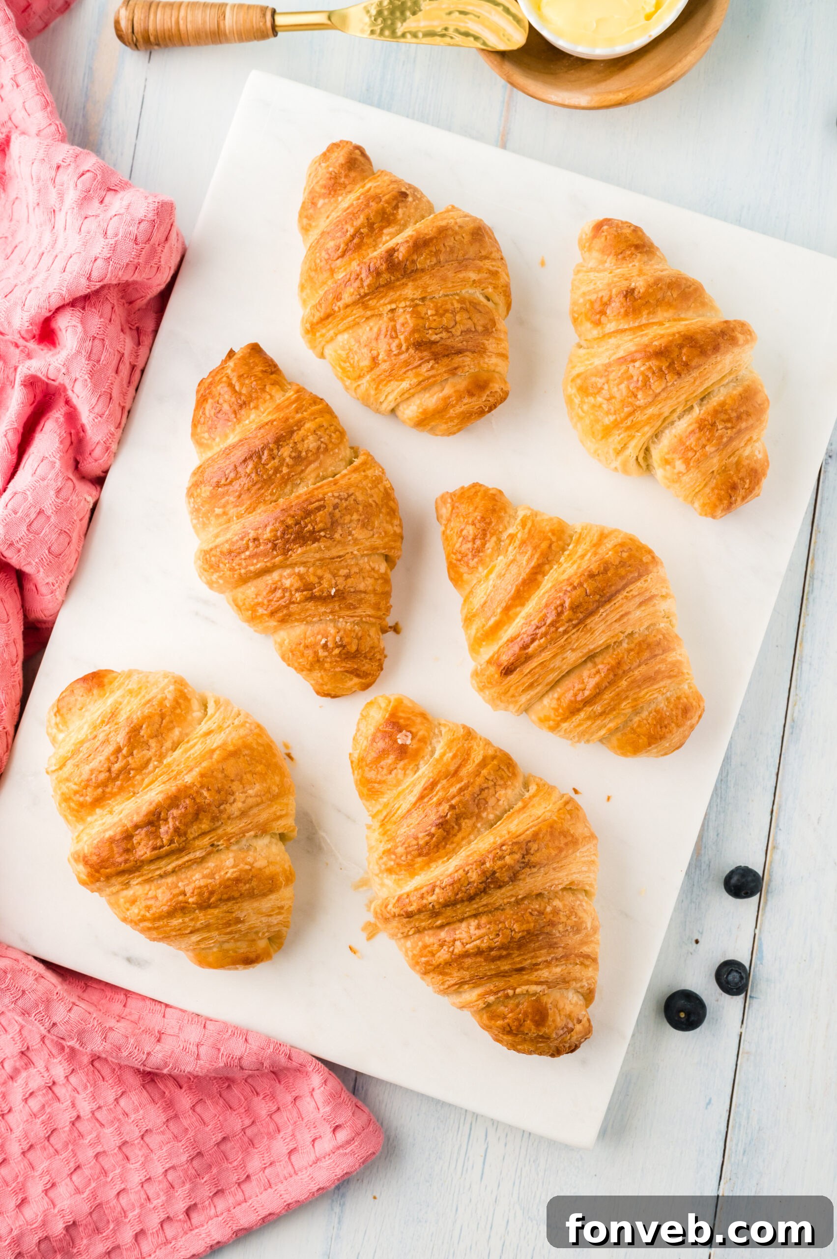 An overhead shot showcasing a platter of golden homemade croissants, highlighting their perfect crescent shape and appealing sheen.
