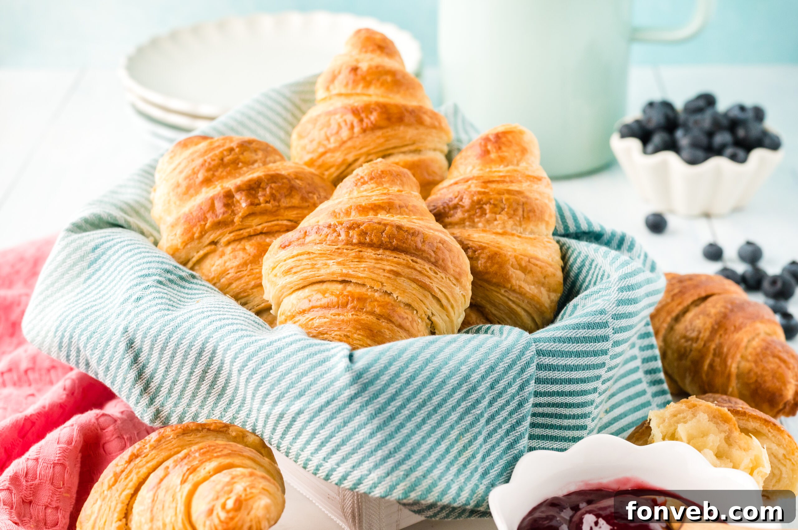 A charming basket filled with golden-brown homemade croissants, invitingly lined with soft linen.