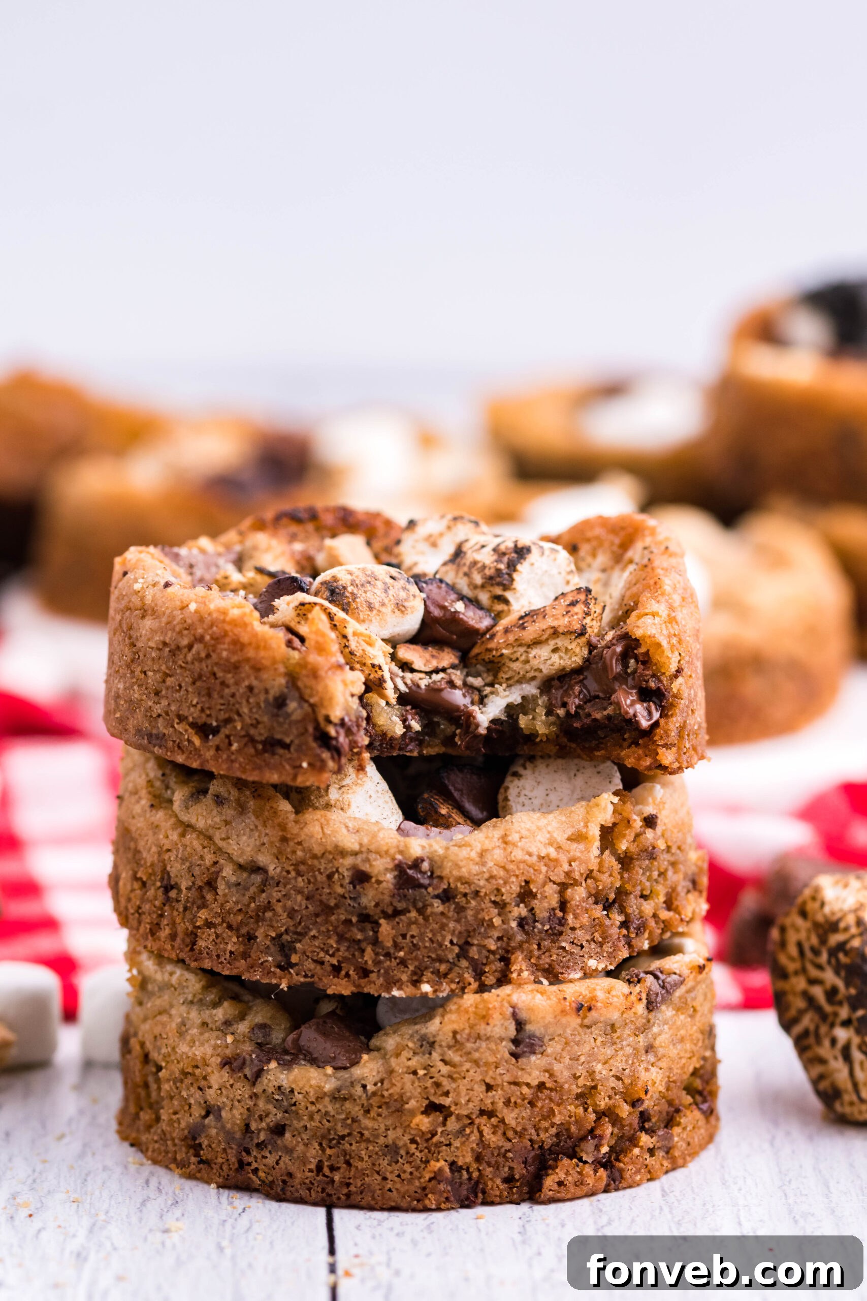 Front view of three Deep Dish S’mores Cookies staked with a bite removed from the top cookie.