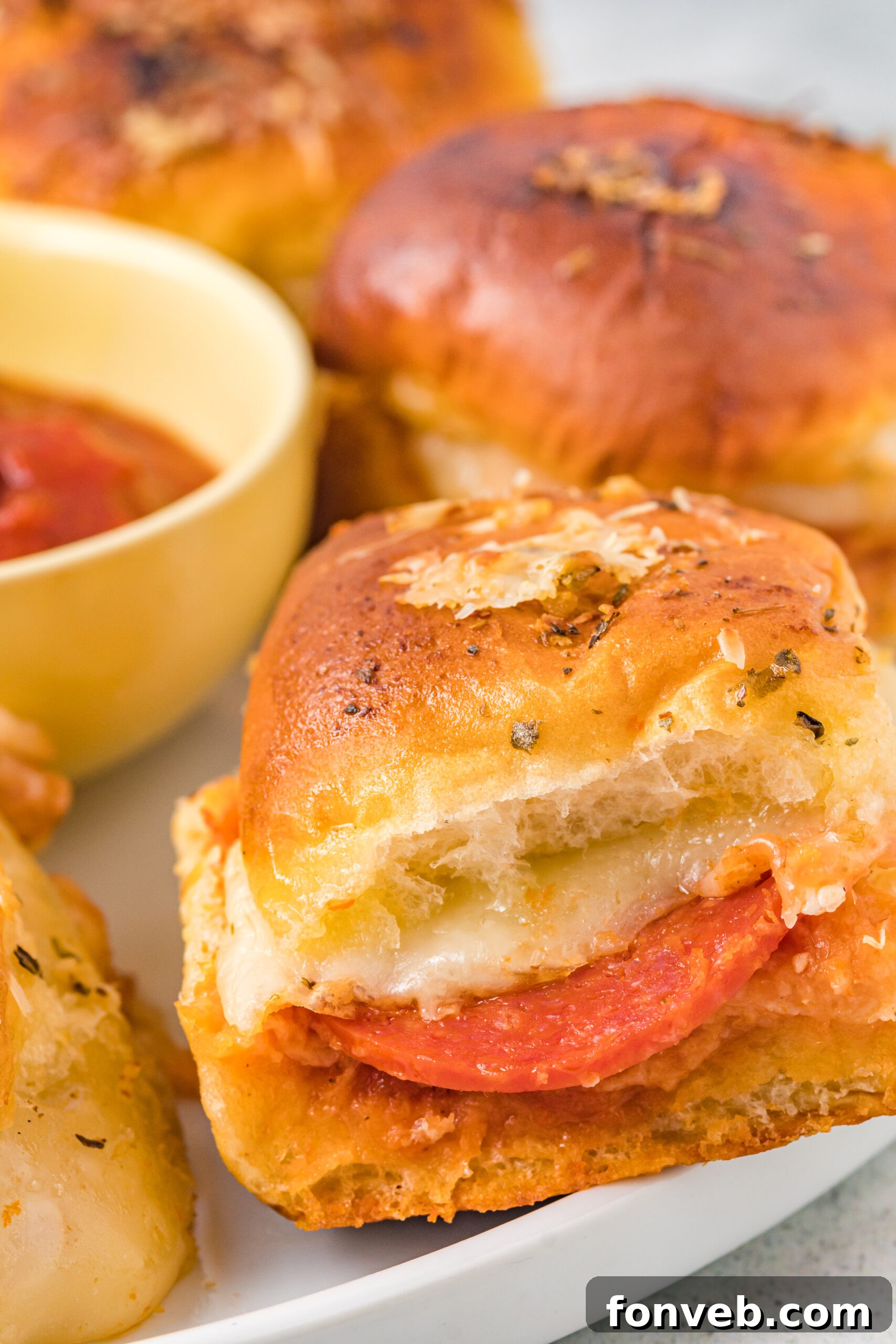 Ultimate Pizza Pull-Aparts 15 A close-up side view of a perfectly baked pizza slider, showing its layers of bread, cheese, and pepperoni.