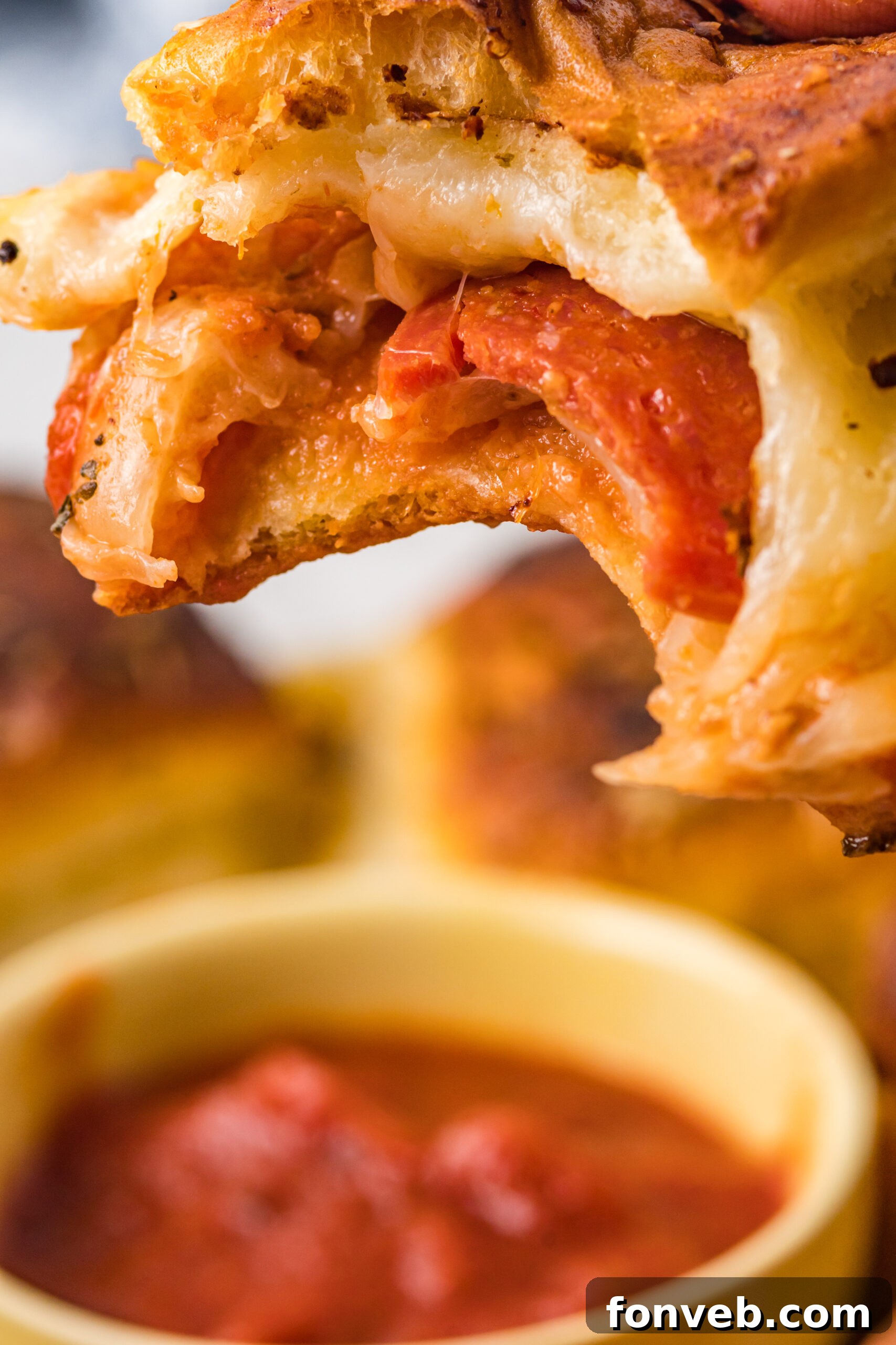 Ultimate Pizza Pull-Aparts 5 A pepperoni pizza slider with a bite missing, revealing the molten cheese and vibrant pepperoni inside.