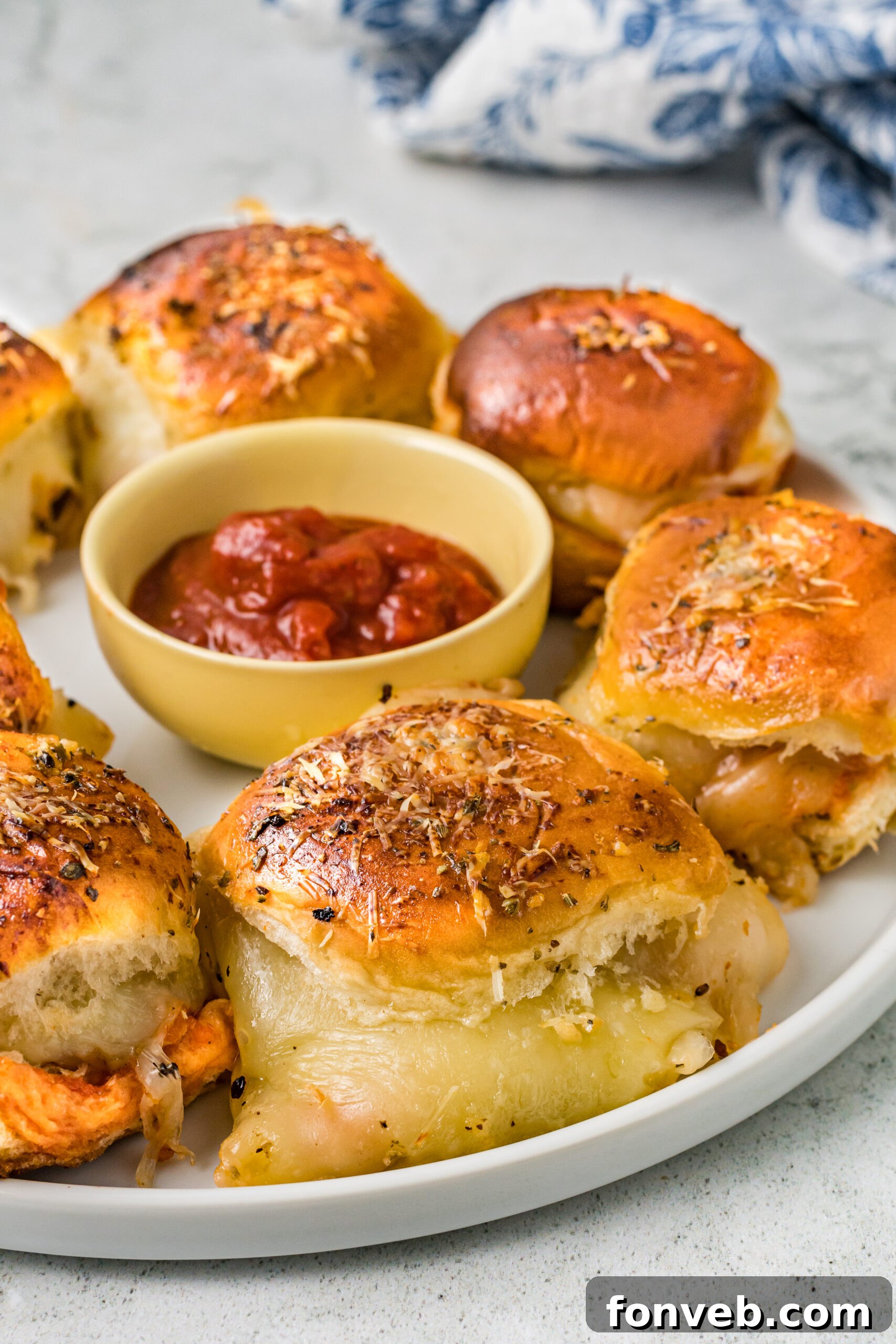 Ultimate Pizza Pull-Aparts 7 A white plate filled with pizza sliders, with a small bowl of marinara sauce nestled in the center for dipping.