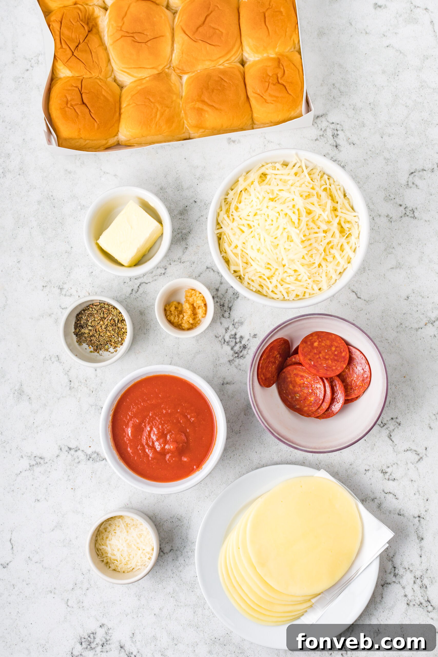 Ultimate Pizza Pull-Aparts 8 An overhead shot displaying all the fresh ingredients meticulously laid out for making the pizza sliders, including rolls, cheeses, pepperoni, sauce, and seasonings.
