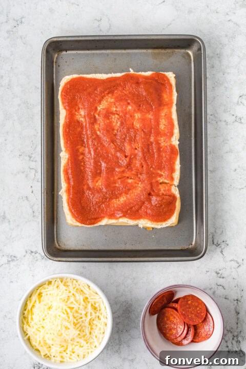 Ultimate Pizza Pull-Aparts 9 Close-up of Hawaiian rolls sliced horizontally in a baking dish.