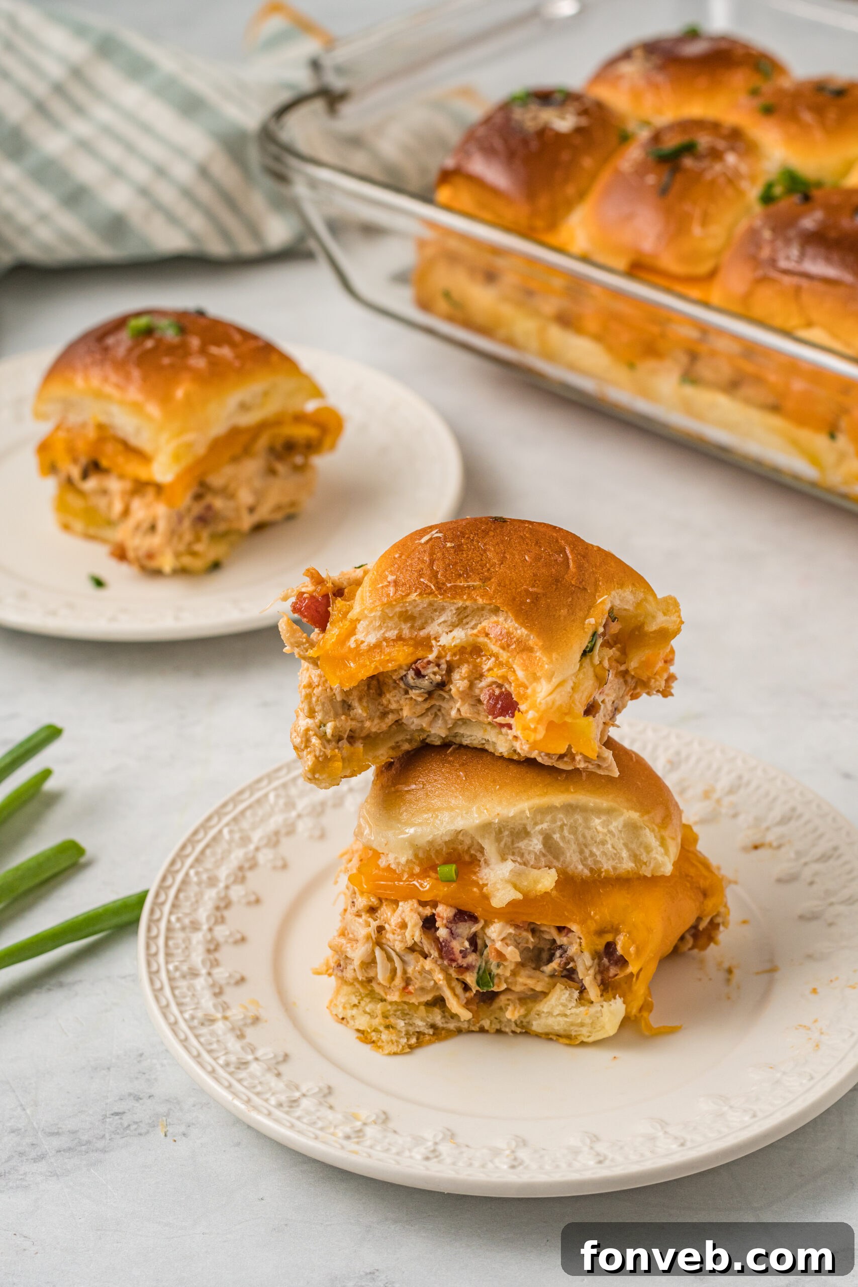 Front view of two Crack Chicken Sliders stacked on a white plate with a bite removed from the top slider. 