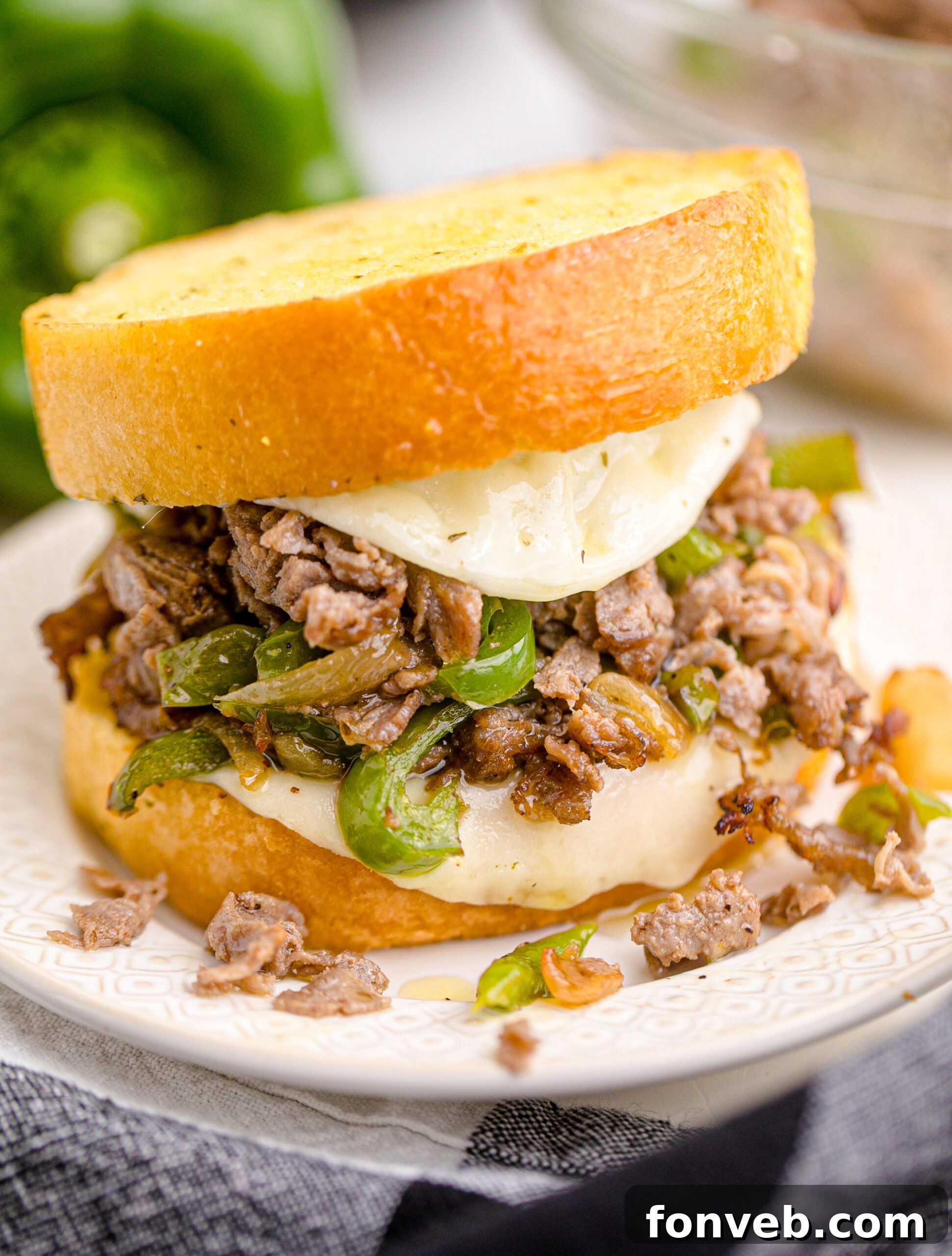 Golden Air Fryer Philly Cheesesteaks 2 Front view of Air Fryer Philly Cheese Steaks on a white plate, showcasing melted cheese and sautéed vegetables.