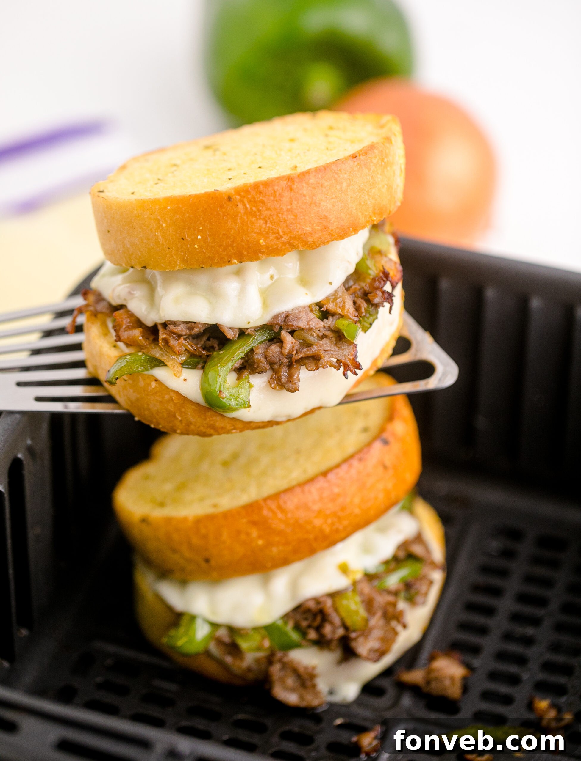 Golden Air Fryer Philly Cheesesteaks 3 Close-up of an Air Fryer Philly Cheese Steak being lifted with a silver spatula, highlighting its gooey texture.