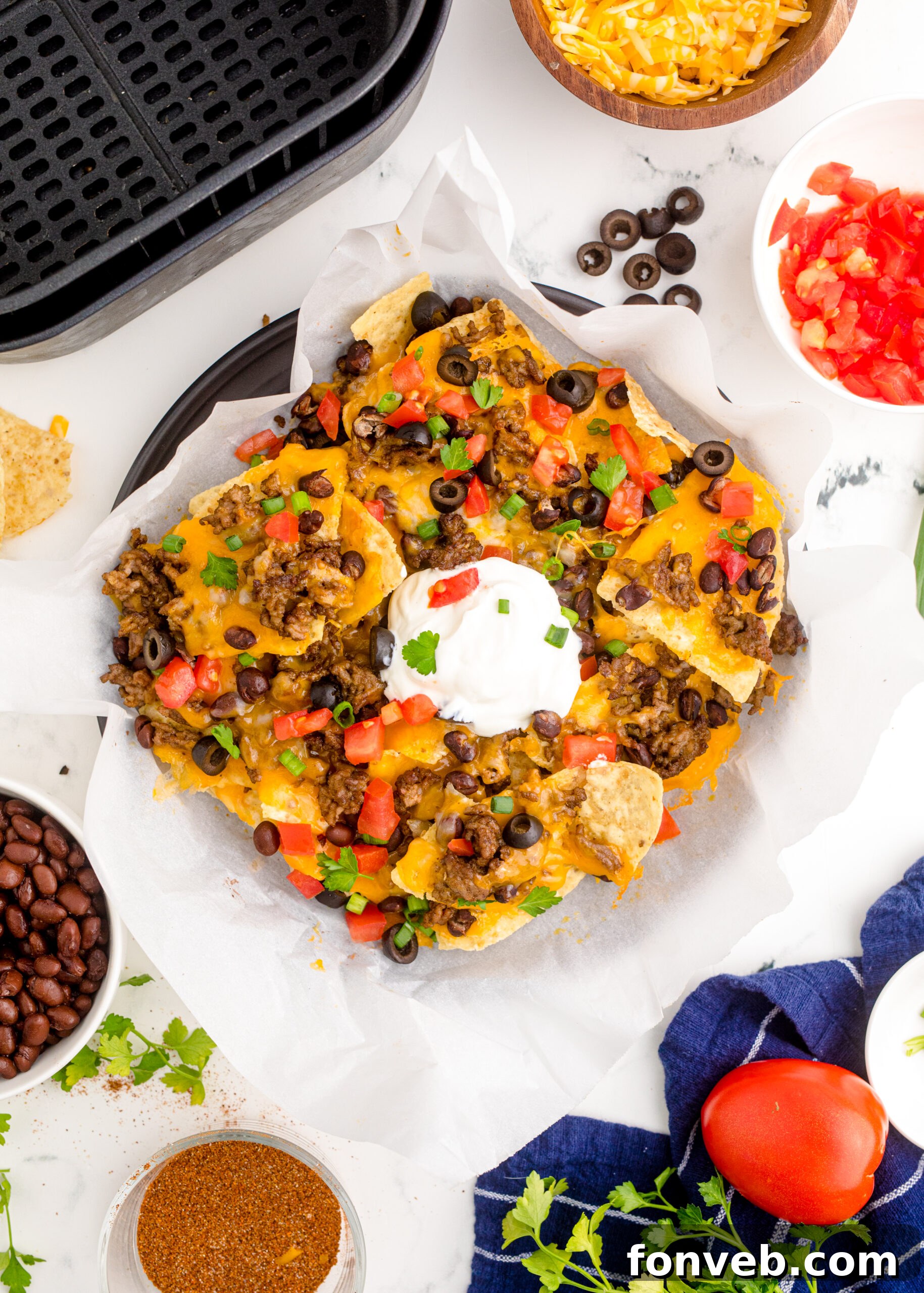 Ultimate Air Fryer Nachos 15 Overhead view of Air Fryer Nachos in an black dish with parchment paper.