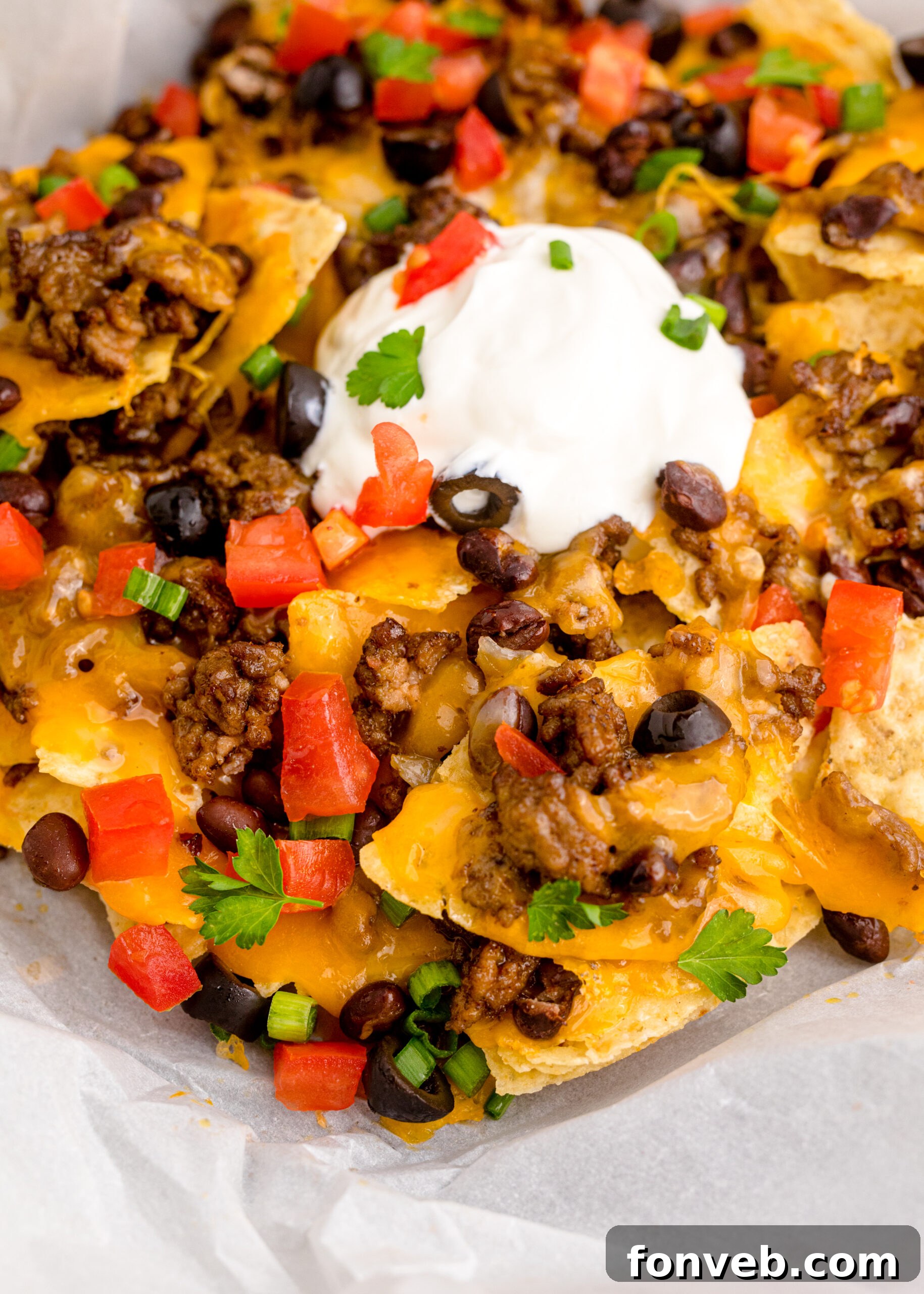 Ultimate Air Fryer Nachos 16 Close up view of Air Fryer Nachos in an black dish with parchment paper.
