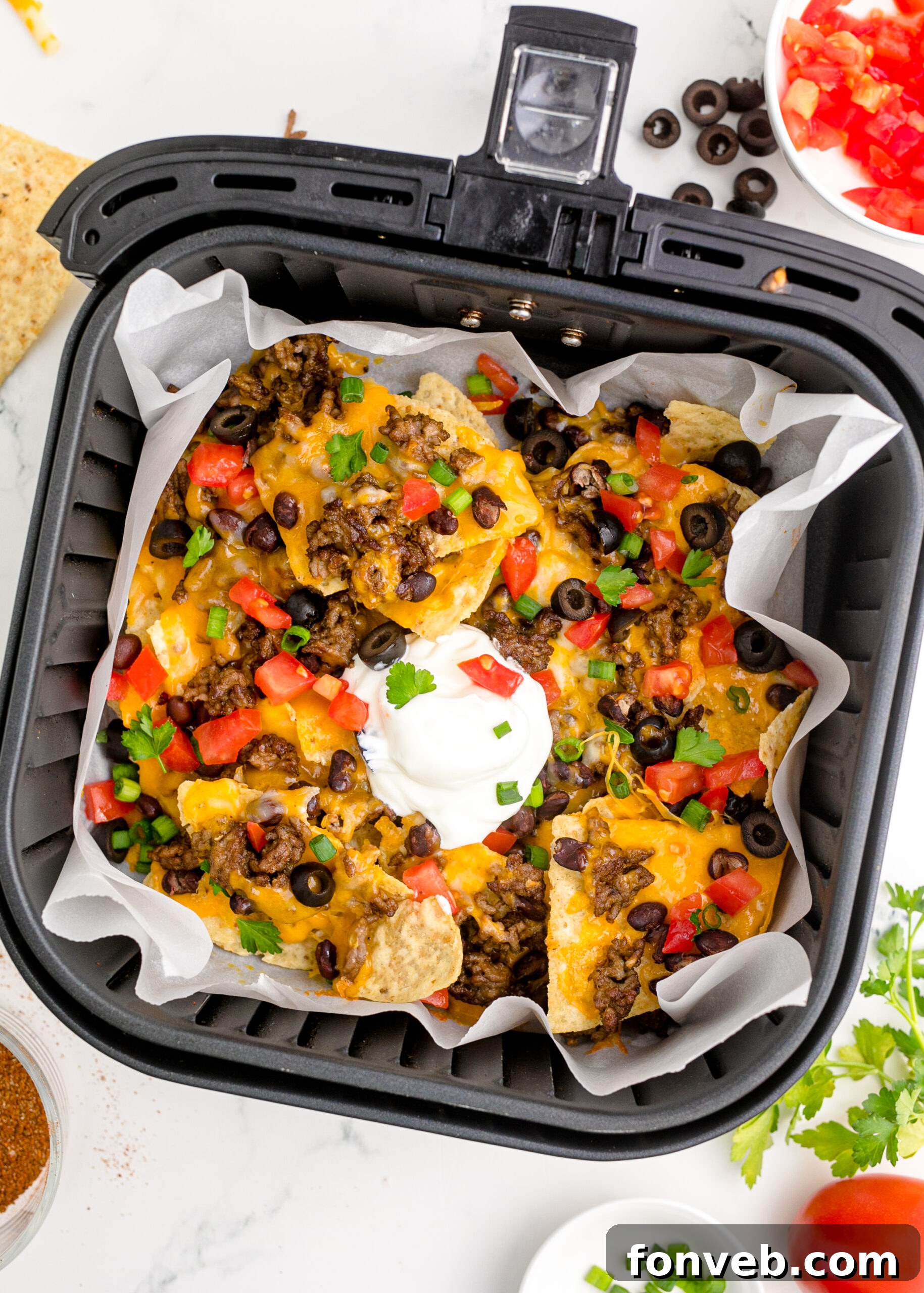 Ultimate Air Fryer Nachos 5 Overhead view of Air Fryer Nachos in an air fryer basket.