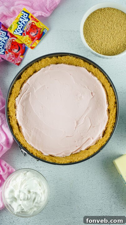 Zesty Easter Kool-Aid Pie 11 The second layer, a vibrant purple Kool-Aid mixture, being carefully spread over the set pink layer.