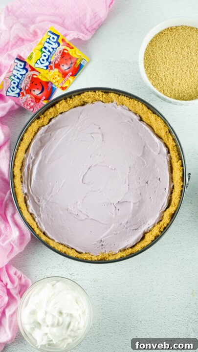 Zesty Easter Kool-Aid Pie 12 The third layer, a bright yellow Kool-Aid mixture, being evenly spread over the set purple layer.