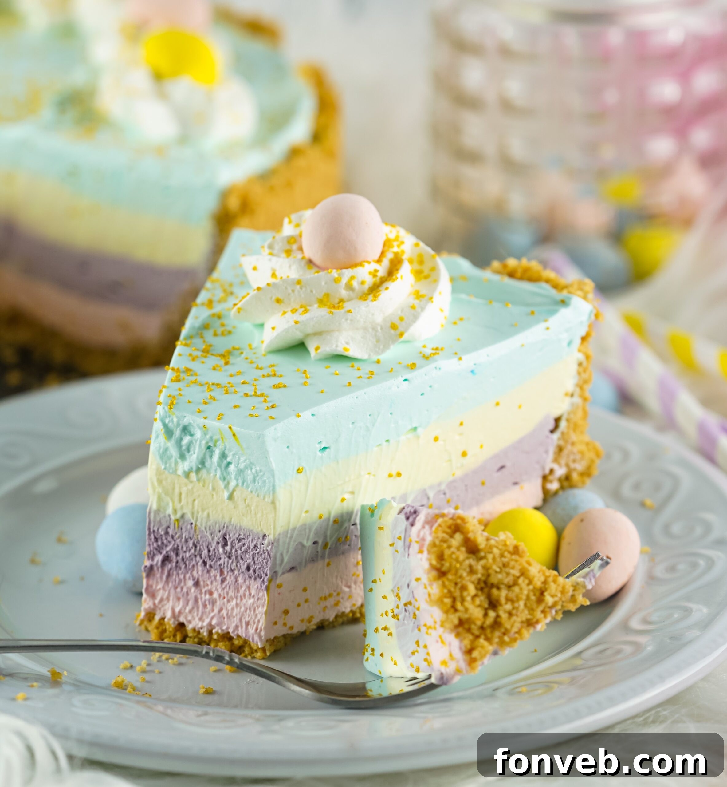 Zesty Easter Kool-Aid Pie 4 Close-up view of a slice of Easter Kool Aid Pie on a white plate, revealing the distinct pink, purple, yellow, and blue layers.